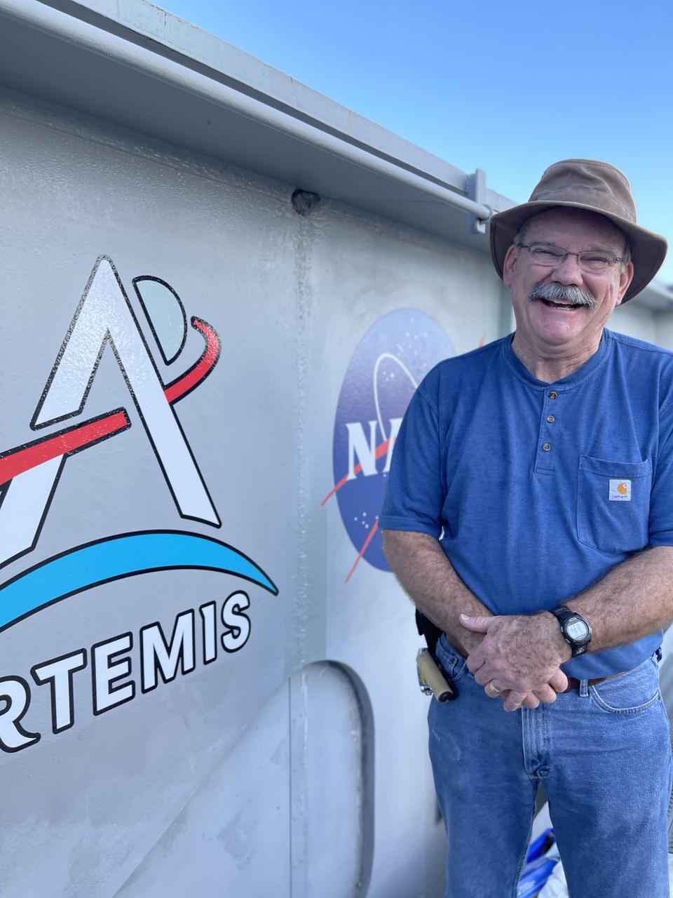 Graphic Artist Kim Keller with one of the eight new NASA Artemis logos (four large, four small) on Crawler-Transporter 2 at Kennedy Space Center in Florida. The new logos were installed in preparation for the upcoming launch of Artemis I. Named after the twin sister of Apollo, Artemis is the Goddess of the Moon. The Artemis missions will take humanity back to the Moon and beyond, beginning a new legacy of deep space exploration.