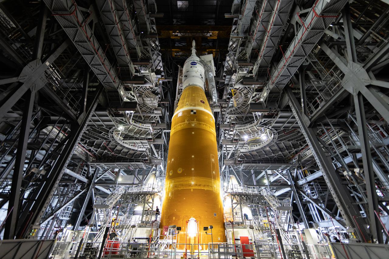 In this view looking up inside the Vehicle Assembly Building at NASA’s Kennedy Space Center in Florida on March 11, 2022, the work platforms are being retracted from around the Artemis I Space Launch System rocket and Orion spacecraft in preparation to roll out to launch pad 39B. The Kennedy ground systems team is working to remove equipment and scaffolding away from the rocket and will continue retracting the platforms until the entire rocket is revealed ahead of the wet dress rehearsal test, which is scheduled to occur approximately two weeks after it arrives to 39B. Artemis I is the first in a series of increasingly complex missions that will enable human exploration to the Moon and Mars.