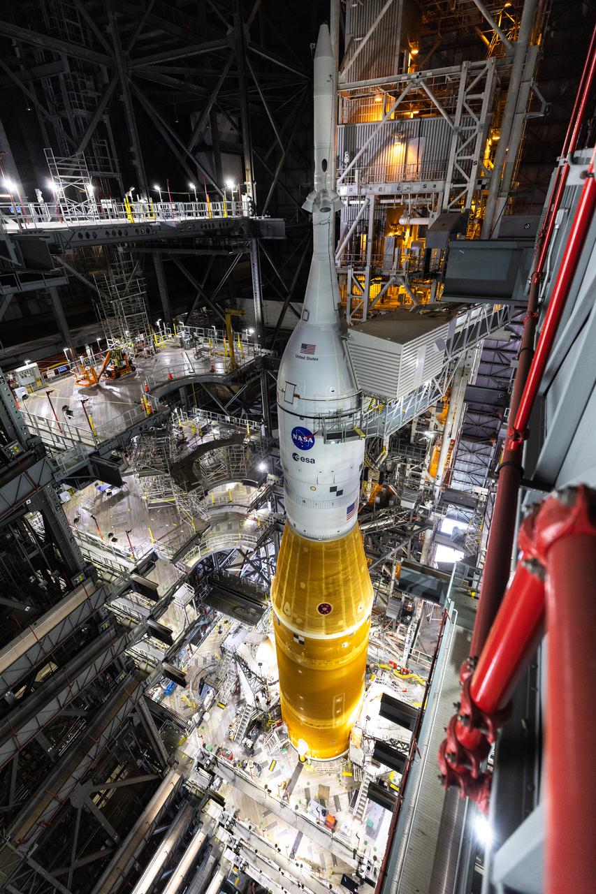 In this view looking down inside the Vehicle Assembly Building at NASA’s Kennedy Space Center in Florida on March 11, 2022, the work platforms are being retracted from around the Artemis I Space Launch System rocket and Orion spacecraft in preparation to roll out to launch pad 39B. The Kennedy ground systems team is working to remove equipment and scaffolding away from the rocket and will continue retracting the platforms until the entire rocket is revealed ahead of the wet dress rehearsal test, which is scheduled to occur approximately two weeks after it arrives to 39B. Artemis I is the first in a series of increasingly complex missions that will enable human exploration to the Moon and Mars.