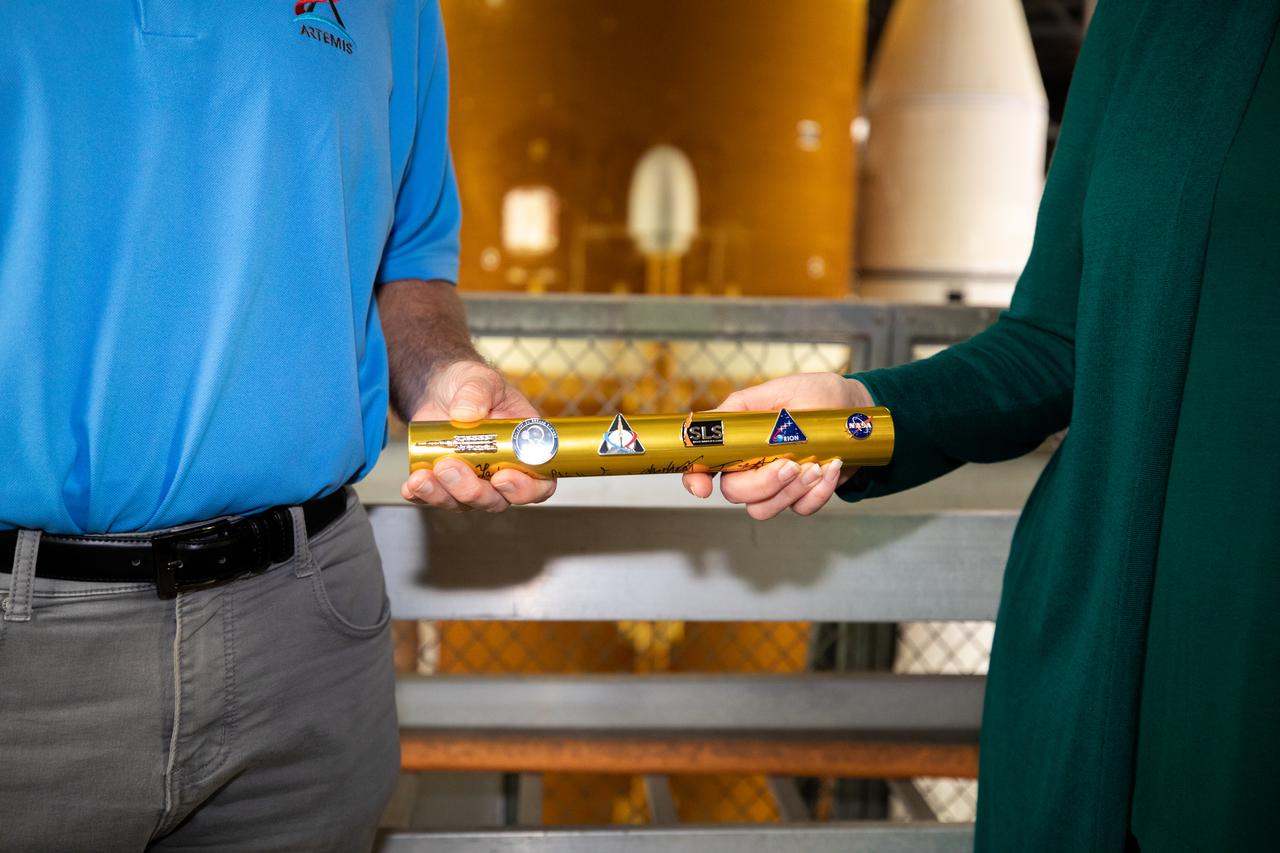 A baton is passed from Cliff Lanham, at left, ground operations manager with Exploration Ground Systems, to Charlie Blackwell-Thompson, Artemis I launch director, inside the Vehicle Assembly Building at NASA’s Kennedy Space Center in Florida on March 16, 2022. Behind them is the Artemis I Space Launch System (SLS) with the Orion spacecraft atop on the mobile launcher. The SLS and Orion will make the trek to Launch Complex 39B for a wet dress rehearsal ahead of launch atop the crawler-transporter 2. Artemis I will be the first integrated test of the SLS and Orion spacecraft. In later missions, NASA will land the first woman and the first person of color on the surface of the Moon, paving the way for a long-term lunar presence and serving as a steppingstone on the way to Mars. 