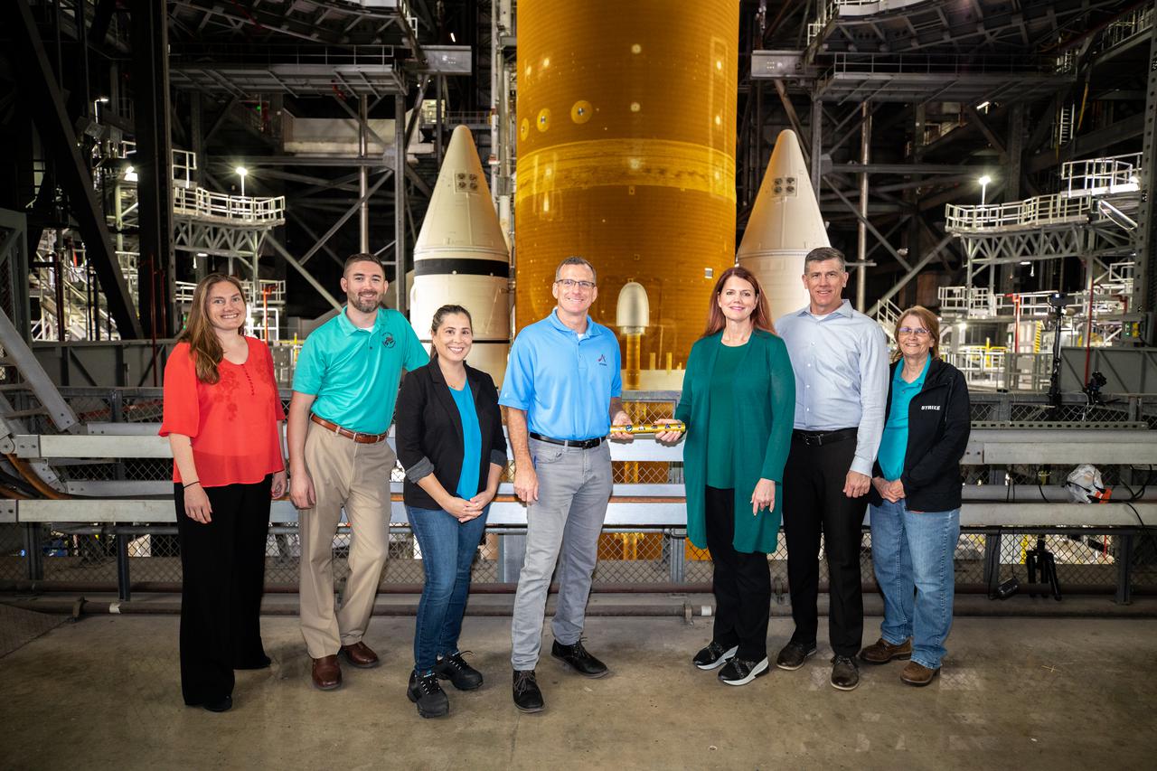 Cliff Lanham, fourth from left,  ground operations manager with Exploration Ground Systems (EGS), passes the baton to Charlie Blackwell-Thompson, Artemis I launch director, inside the Vehicle Assembly Building at NASA’s Kennedy Space Center in Florida on March 16, 2022. Joining them from left, are Stacey Bagg, Matt Czech, and Liliana Villareal, with EGS. Next to Blackwell-Thomson are Jeremy Graeber, deputy launch director, and Teresa Annulis. The Space Launch System (SLS) and Orion will make the trek to Launch Complex 39B for a wet dress rehearsal ahead of launch atop the crawler-transporter 2. Artemis I will be the first integrated test of the SLS and Orion spacecraft. In later missions, NASA will land the first woman and the first person of color on the surface of the Moon, paving the way for a long-term lunar presence and serving as a steppingstone on the way to Mars. 