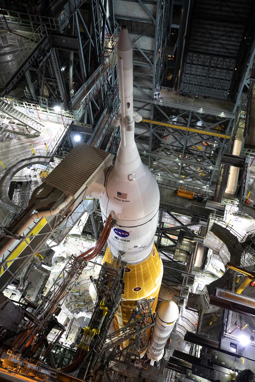 In this view looking down in High Bay 3 of the Vehicle Assembly Building at NASA’s Kennedy Space Center in Florida, the Artemis I Space Launch System (SLS) and Orion spacecraft can be seen without any work platforms surrounding them on March 17, 2022. The Artemis I stack atop the mobile launcher will roll out to Launch Complex 39B atop the crawler-transporter 2 for a wet dress rehearsal ahead of launch. Artemis I will be the first integrated test of the SLS and Orion spacecraft. In later missions, NASA will land the first woman the first person of color on the surface of the Moon, paving the way for a long-term lunar presence and serving as a steppingstone on the way to Mars.