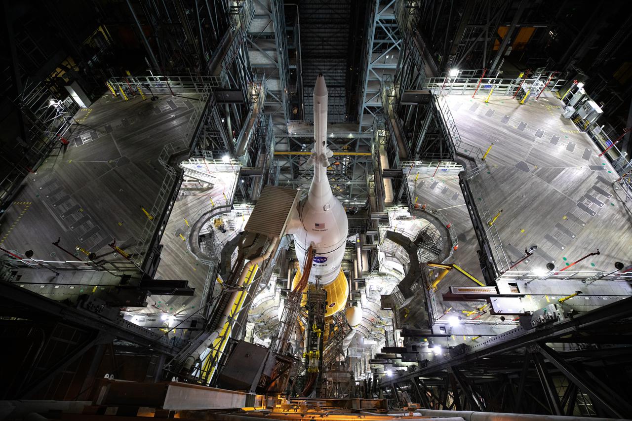 In this view looking down in High Bay 3 of the Vehicle Assembly Building at NASA’s Kennedy Space Center in Florida, the Artemis I Space Launch System (SLS) and Orion spacecraft can be seen without any work platforms surrounding them on March 17, 2022. The Artemis I stack atop the mobile launcher will roll out to Launch Complex 39B atop the crawler-transporter 2 for a wet dress rehearsal ahead of launch. Artemis I will be the first integrated test of the SLS and Orion spacecraft. In later missions, NASA will land the first woman the first person of color on the surface of the Moon, paving the way for a long-term lunar presence and serving as a steppingstone on the way to Mars.