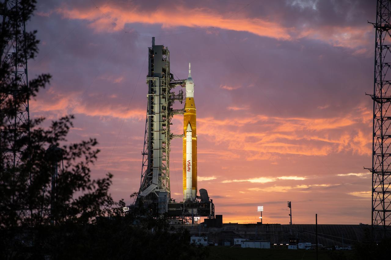 The sunrise casts a golden glow on the Artemis I Space Launch System (SLS) and Orion spacecraft at Launch Pad 39B at NASA’s Kennedy Space Center in Florida on March 23, 2022. The SLS and Orion atop the mobile launcher were transported to the pad on crawler-transporter 2 for a prelaunch test called a wet dress rehearsal. Artemis I will be the first integrated test of the SLS and Orion spacecraft. In later missions, NASA will land the first woman and the first person of color on the surface of the Moon, paving the way for a long-term lunar presence and serving as a steppingstone on the way to Mars. 