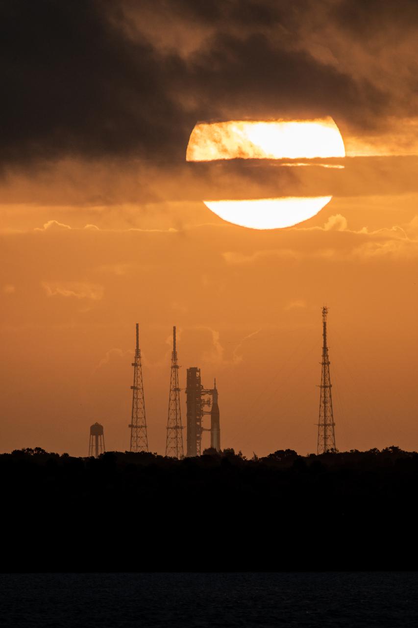A view of the Artemis I Space Launch System (SLS) and Orion spacecraft on Launch Pad 39B during sunrise at NASA’s Kennedy Space Center in Florida on March 24, 2022. The SLS and Orion atop the mobile launcher were transported to the pad on crawler-transporter 2 for a prelaunch test called a wet dress rehearsal. Artemis I will be the first integrated test of the SLS and Orion spacecraft. In later missions, NASA will land the first woman and the first person of color on the surface of the Moon, paving the way for a long-term lunar presence and serving as a steppingstone on the way to Mars. 
