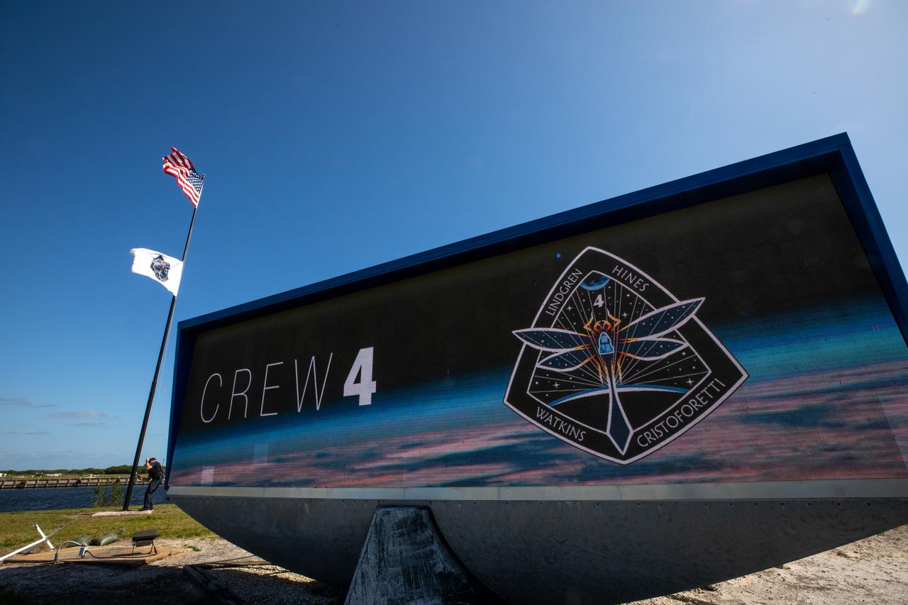 The News Center countdown clock is shown as NASA’s SpaceX Crew-4 flag is raised at NASA’s Kennedy Space Center in Florida on April 19, 2022. The SpaceX Falcon 9 with Crew Dragon, named Freedom by the Crew-4 crew, atop is scheduled to lift off Saturday, April 23, 2002, at 5:26 p.m. EDT, from Launch Complex 39A at Kennedy. Dragon will carry NASA astronauts Kjell Lindgren, Bob Hines, and Jessica Watkins, and ESA (European Space Agency) astronaut Samantha Cristoforetti to the International Space Station as part of NASA’s Commercial Crew Program.