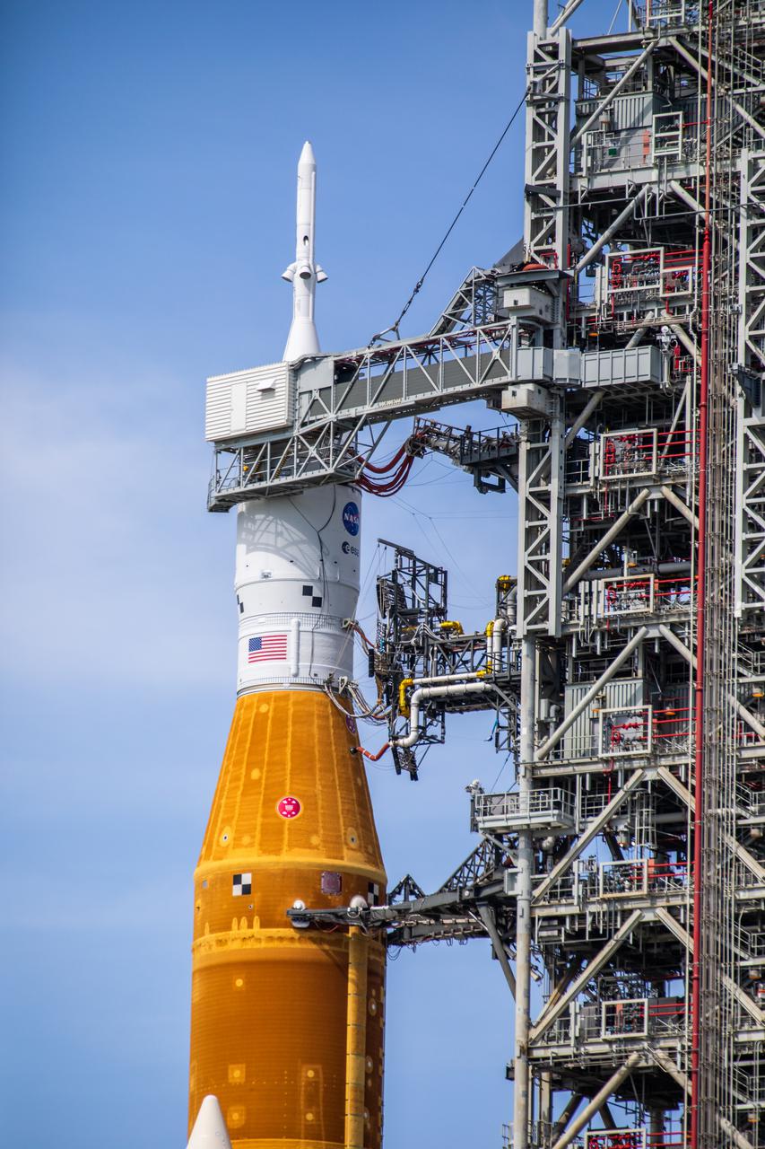A close-up view of the Artemis I Space Launch System (SLS) and Orion spacecraft on Launch Pad 39B at NASA’s Kennedy Space Center in Florida on April 21, 2022. A portion of the mobile launcher and umbilical connections are in view, as well as the crew access arm. The SLS and Orion atop the mobile launcher were transported to the pad on crawler-transporter 2 for a prelaunch test called a wet dress rehearsal. Artemis I will be the first integrated test of the SLS and Orion spacecraft. In future Artemis missions, NASA will land the first woman and the first person of color on the surface of the Moon, paving the way for a long-term lunar presence and serving as a steppingstone on the way to Mars.