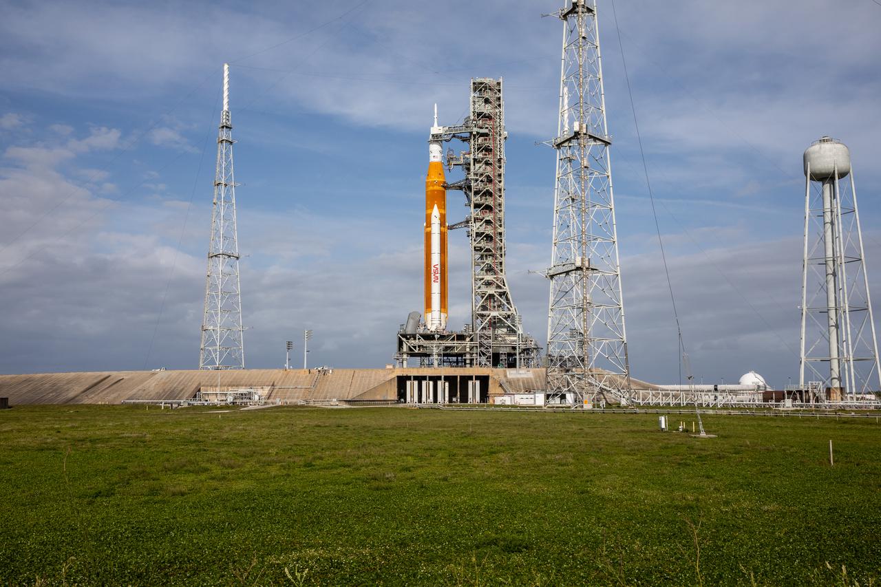 A view of the Artemis I Space Launch System (SLS) and Orion spacecraft on Launch Pad 39B at NASA’s Kennedy Space Center in Florida on April 21, 2022. Also in view are two of three lightning protection towers. The SLS and Orion atop the mobile launcher were transported to the pad on crawler-transporter 2 for a prelaunch test called a wet dress rehearsal. Artemis I will be the first integrated test of the SLS and Orion spacecraft. In future Artemis missions, NASA will land the first woman and the first person of color on the surface of the Moon, paving the way for a long-term lunar presence and serving as a steppingstone on the way to Mars.