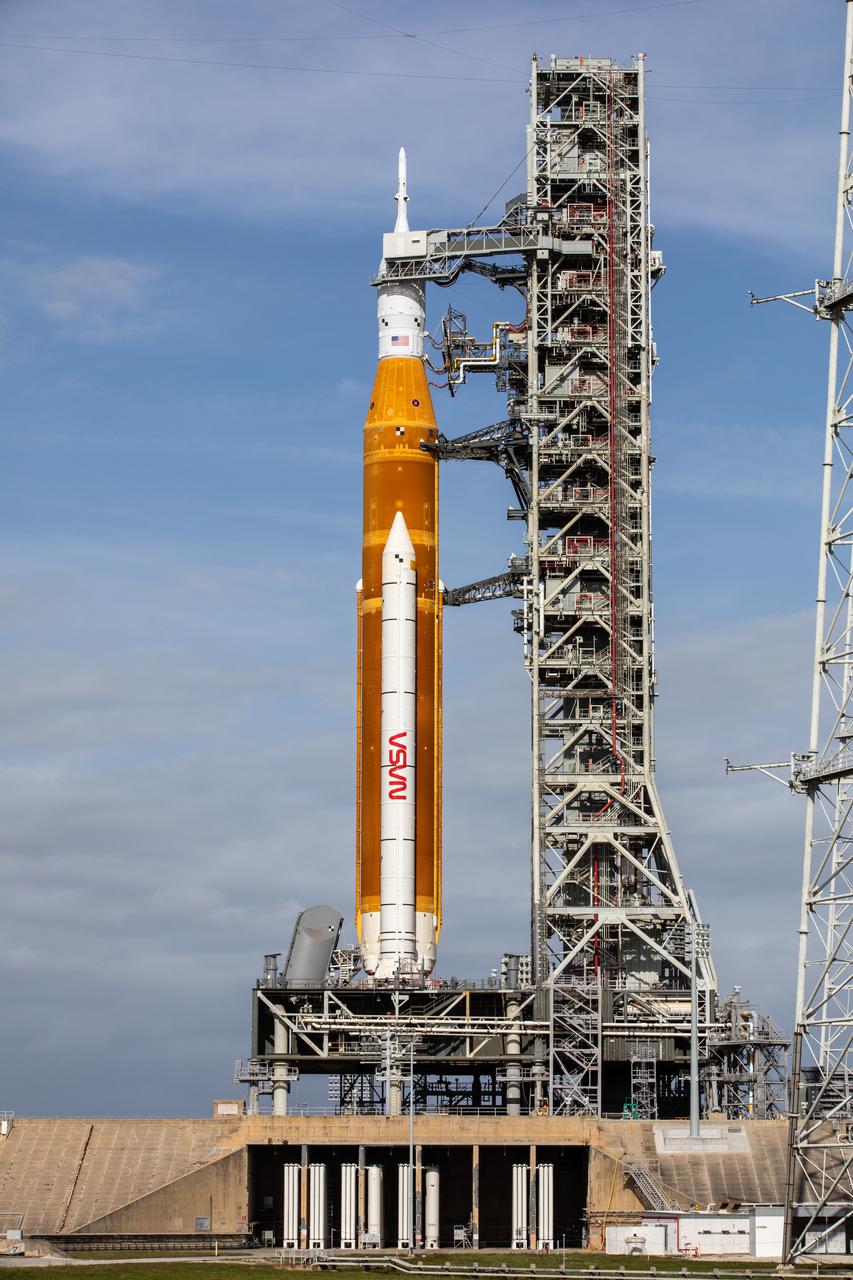 A view of the Artemis I Space Launch System (SLS) and Orion spacecraft atop the mobile launcher (ML) on Launch Pad 39B at NASA’s Kennedy Space Center in Florida on April 21, 2022. Also in view are several of the umbilical connections from the ML to the rocket. The SLS and Orion atop the mobile launcher were transported to the pad on crawler-transporter 2 for a prelaunch test called a wet dress rehearsal. Artemis I will be the first integrated test of the SLS and Orion spacecraft. In future Artemis missions, NASA will land the first woman and the first person of color on the surface of the Moon, paving the way for a long-term lunar presence and serving as a steppingstone on the way to Mars.