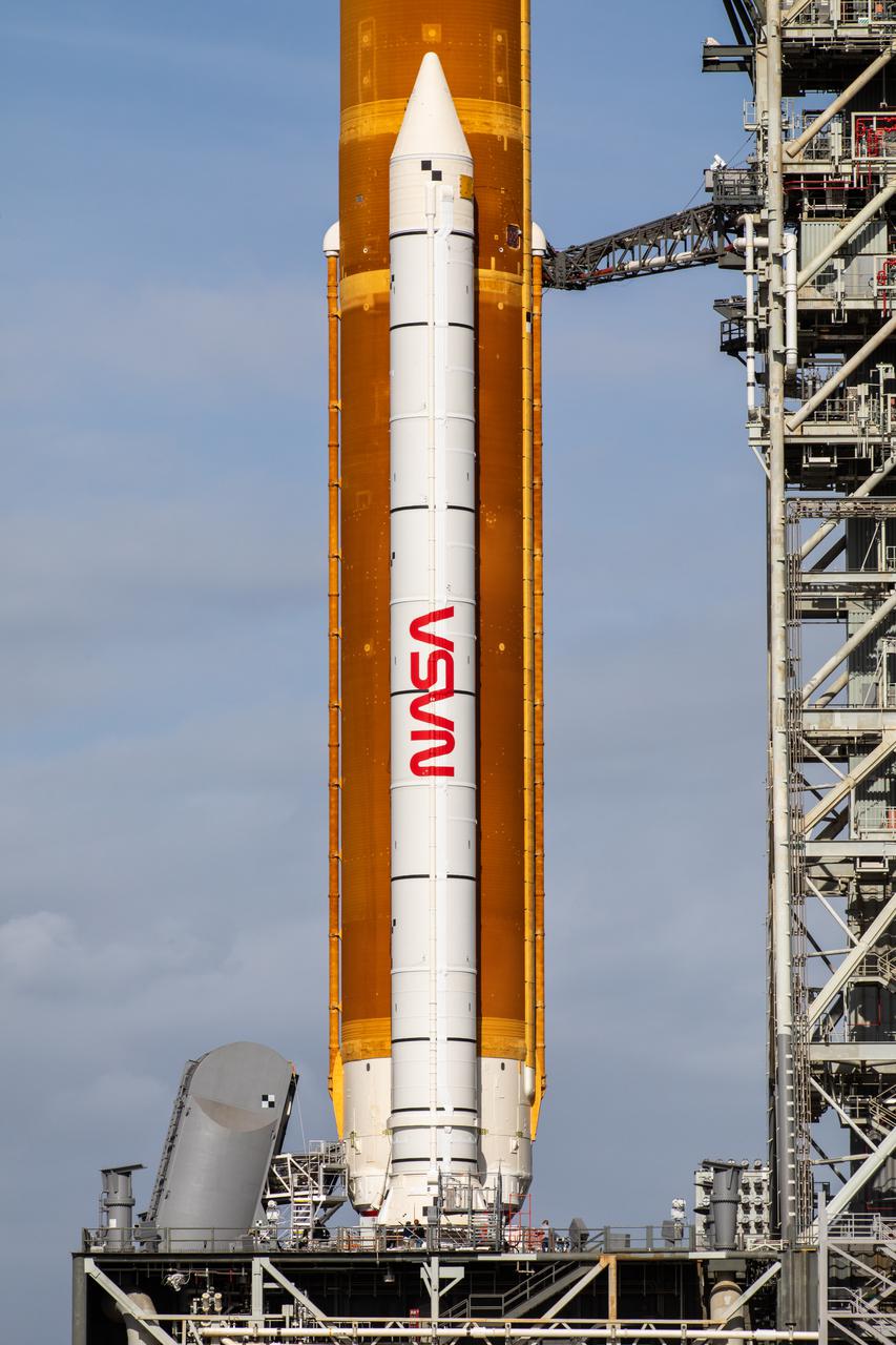A close-up view of the Artemis I Space Launch System (SLS) and one of two solid rocket boosters on Launch Pad 39B at NASA’s Kennedy Space Center in Florida on April 21, 2022. A portion of the mobile launcher and one umbilical connection also is in view. The SLS and Orion atop the mobile launcher were transported to the pad on crawler-transporter 2 for a prelaunch test called a wet dress rehearsal. Artemis I will be the first integrated test of the SLS and Orion spacecraft. In future Artemis missions, NASA will land the first woman and the first person of color on the surface of the Moon, paving the way for a long-term lunar presence and serving as a steppingstone on the way to Mars.