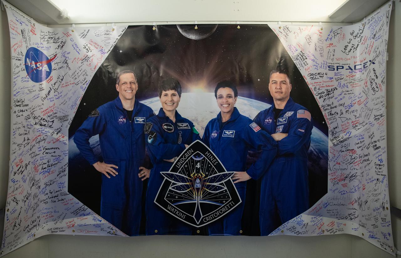 A poster depicting Crew-4 mission astronauts, from left, Bob Hines, Samantha Cristoforetti, Jessica Watkins, and Kjell Lindgren is shown in the Astronaut Crew Quarters inside Kennedy Space Center’s Neil A. Armstrong Operations and Checkout Building on April 27, 2022. The four astronauts will launch aboard SpaceX’s Crew Dragon – powered by the company’s Falcon 9 rocket – to the International Space Station as part of NASA’s Commercial Crew Program. They are scheduled to lift off today at 3:52 a.m. EDT from Launch Complex 39A at Kennedy.