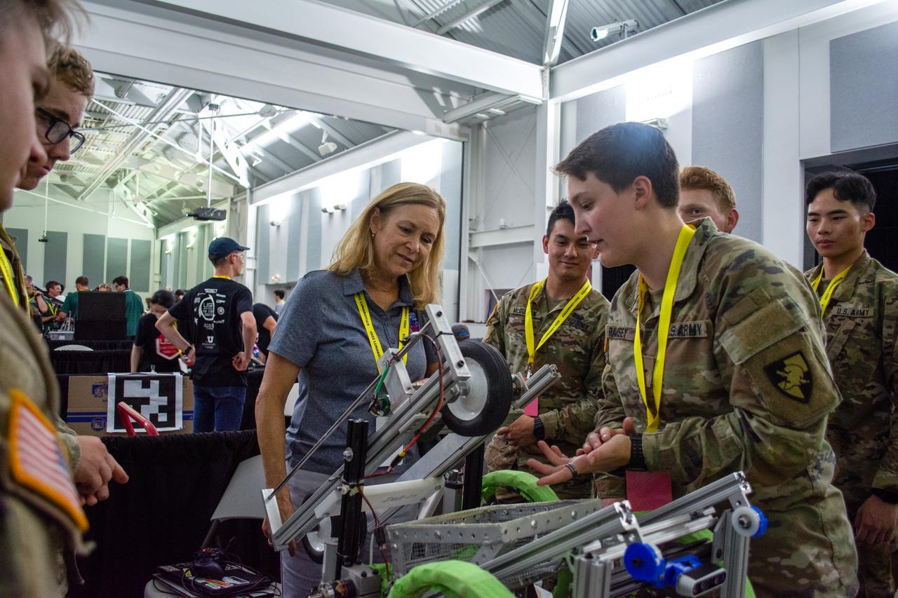 Kennedy Space Center Director Janet Petro, in the center, visits with students from the United States Military Academy (West Point), during NASA’s LUNABOTICS competition on May 23, 2022, at the Center for Space Education near the Kennedy Space Center Visitor Complex in Florida, on May 23, 2022. The students are preparing their robotic miner for its turn to dig in the mining arena. More than 35 teams from around the U.S. have designed and built remote-controlled robots for the mining competition. Teams use their autonomous or remote-controlled robots to maneuver and dig in a supersized sandbox filled with rocks and simulated lunar soil, or regolith. The objective of the challenge is to see which team’s robot can collect and deposit the most rocky regolith within a specified amount of time. 