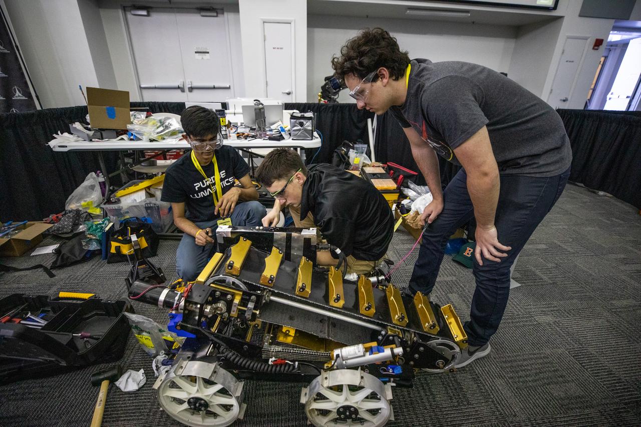 Students from Purdue University prepare their robotic miner for its turn to dig in the mining pit during NASA’s LUNABOTICS competition on May 23, 2022, at the Center for Space Education near the Kennedy Space Center Visitor Complex in Florida. More than 35 teams from around the U.S. have designed and built remote-controlled robots for the mining competition. Teams use their autonomous or remote-controlled robots to maneuver and dig in a supersized sandbox filled with rocks and simulated lunar soil, or regolith. The objective of the challenge is to see which team’s robot can collect and deposit the most rocky regolith within a specified amount of time. 