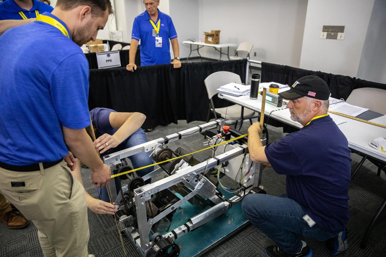 The Saginaw Valley State University team’s robotic miner is being measured and weighed to qualify for its turn to dig in the mining arena during NASA’s LUNABOTICS competition on May 23, 2022, at the Center for Space Education near the Kennedy Space Center Visitor Complex in Florida. More than 35 teams from around the U.S. have designed and built remote-controlled robots for the mining competition. Teams use their autonomous or remote-controlled robots to maneuver and dig in a supersized sandbox filled with rocks and simulated lunar soil, or regolith. The objective of the challenge is to see which team’s robot can collect and deposit the most rocky regolith within a specified amount of time. 