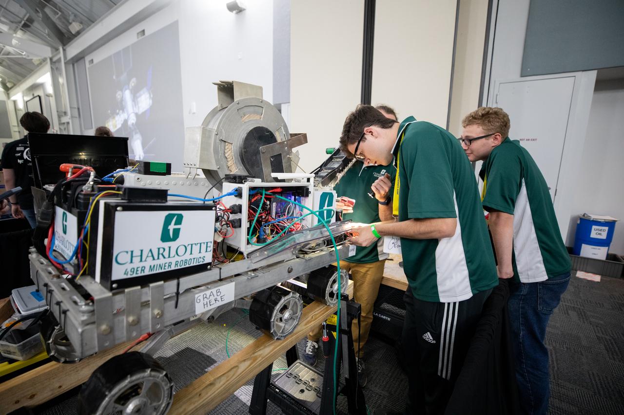 Students from the University of North Carolina at Charlotte prepare their robotic miner for its turn to dig in the mining arena during NASA’s LUNABOTICS competition on May 23, 2022, at the Center for Space Education near the Kennedy Space Center Visitor Complex in Florida. More than 35 teams from around the U.S. have designed and built remote-controlled robots for the mining competition. Teams use their autonomous or remote-controlled robots to maneuver and dig in a supersized sandbox filled with rocks and simulated lunar soil, or regolith. The objective of the challenge is to see which team’s robot can collect and deposit the most rocky regolith within a specified amount of time. 