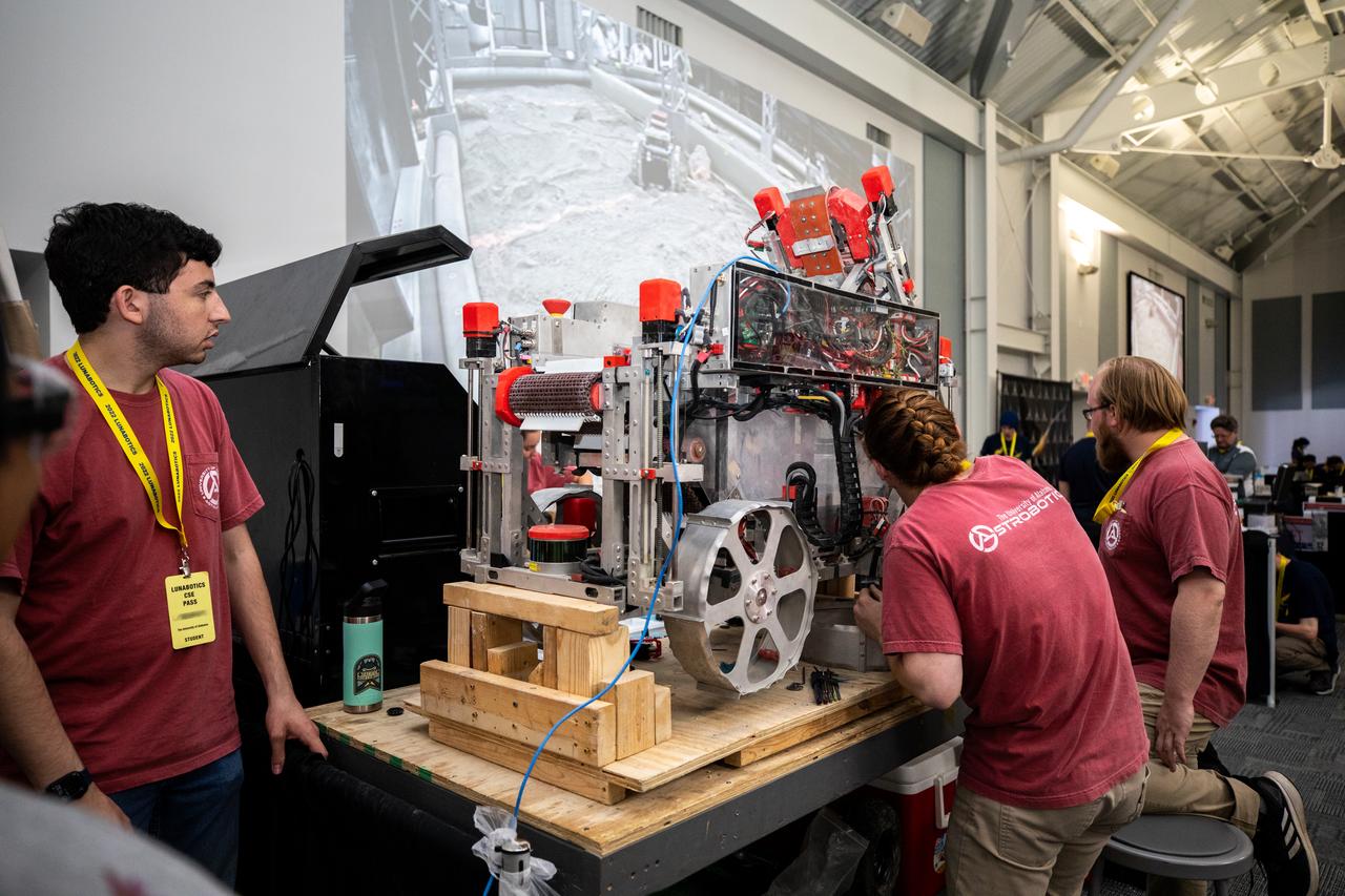 Students from the University of Alabama prepare their robotic miner for its turn to dig in the mining arena during NASA’s LUNABOTICS competition on May 24, 2022, at the Center for Space Education near the Kennedy Space Center Visitor Complex in Florida. More than 35 teams from around the U.S. have designed and built remote-controlled robots for the mining competition. Teams use their autonomous or remote-controlled robots to maneuver and dig in a supersized sandbox filled with rocks and simulated lunar soil, or regolith. The objective of the challenge is to see which team’s robot can collect and deposit the most rocky regolith within a specified amount of time. 