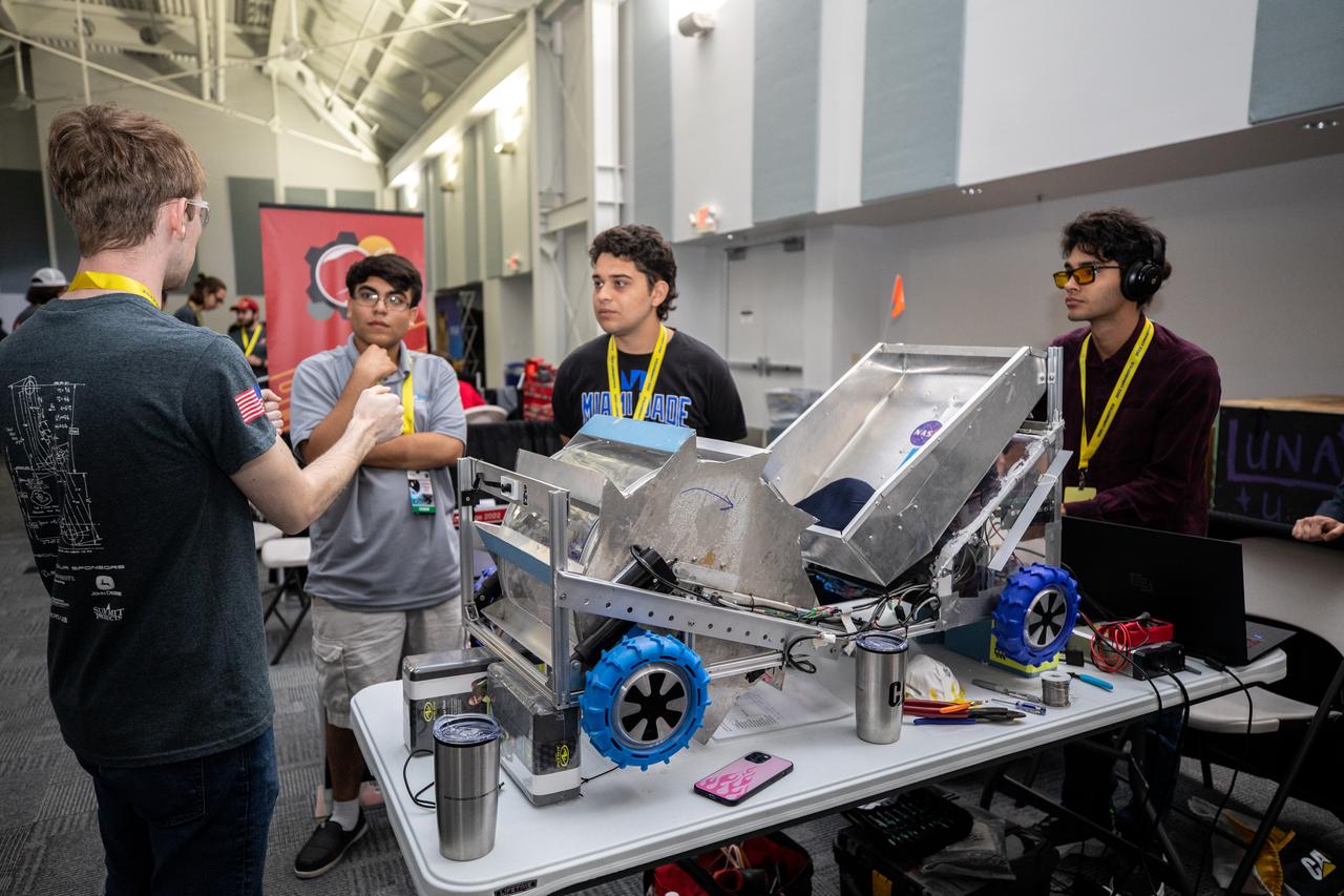 Students from Miami-Dade College at Kendall prepare their robotic miner for its turn to dig in the mining arena during NASA’s LUNABOTICS competition on May 24, 2022, at the Center for Space Education near the Kennedy Space Center Visitor Complex in Florida. More than 35 teams from around the U.S. have designed and built remote-controlled robots for the mining competition. Teams use their autonomous or remote-controlled robots to maneuver and dig in a supersized sandbox filled with rocks and simulated lunar soil, or regolith. The objective of the challenge is to see which team’s robot can collect and deposit the most rocky regolith within a specified amount of time. 