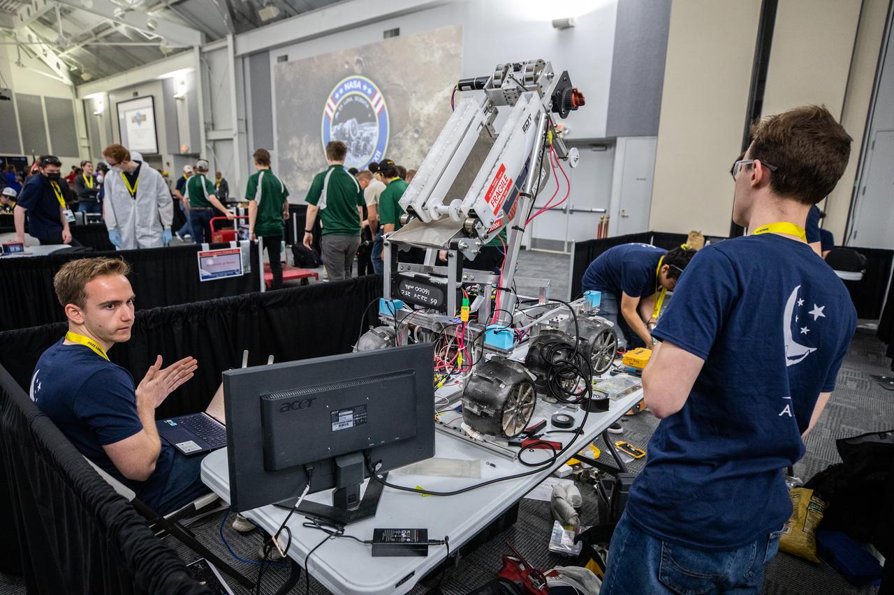 Students from the University of Illinois at Chicago prepare their robotic miner for its turn to dig in the mining arena during NASA’s LUNABOTICS competition on May 26, 2022, at the Center for Space Education near the Kennedy Space Center Visitor Complex in Florida. More than 35 teams from around the U.S. have designed and built remote-controlled robots for the mining competition. Teams use their autonomous or remote-controlled robots to maneuver and dig in a supersized sandbox filled with rocks and simulated lunar soil, or regolith. The objective of the challenge is to see which team’s robot can collect and deposit the most rocky regolith within a specified amount of time. 