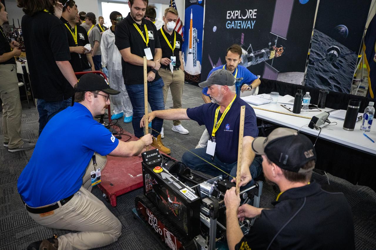Students from the University of Nebraska-Lincoln prepare their robotic miner for its turn to dig in the mining arena during NASA’s LUNABOTICS competition on May 26, 2022, at the Center for Space Education near the Kennedy Space Center Visitor Complex in Florida. More than 35 teams from around the U.S. have designed and built remote-controlled robots for the mining competition. Teams use their semi-autonomous or remote-controlled robots to maneuver and dig in a supersized sandbox filled with rocks and simulated lunar soil, or regolith. The objective of the challenge is to see which team’s robot can collect and deposit the most rocky regolith within a specified amount of time.