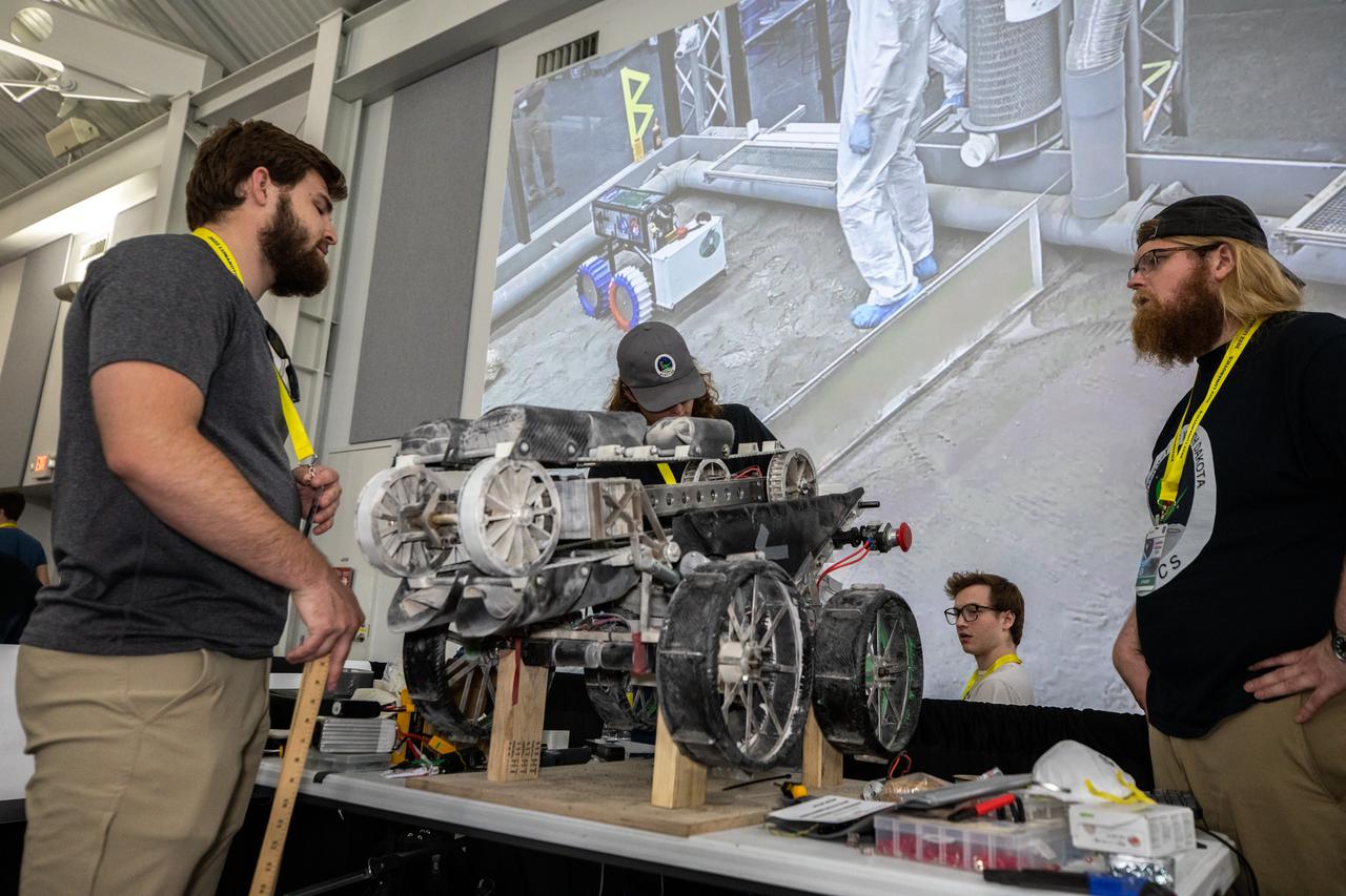 Students from the University of North Dakota prepare their robot miner for its turn to dig in the mining arena during NASA’s LUNABOTICS competition on May 26, 2022, at the Center for Space Education near the Kennedy Space Center Visitor Complex in Florida. More than 35 teams from around the U.S. have designed and built remote-controlled robots for the mining competition. Teams use their semi-autonomous or remote-controlled robots to maneuver and dig in a supersized sandbox filled with rocks and simulated lunar soil, or regolith. The objective of the challenge is to see which team’s robot can collect and deposit the most rocky regolith within a specified amount of time. 