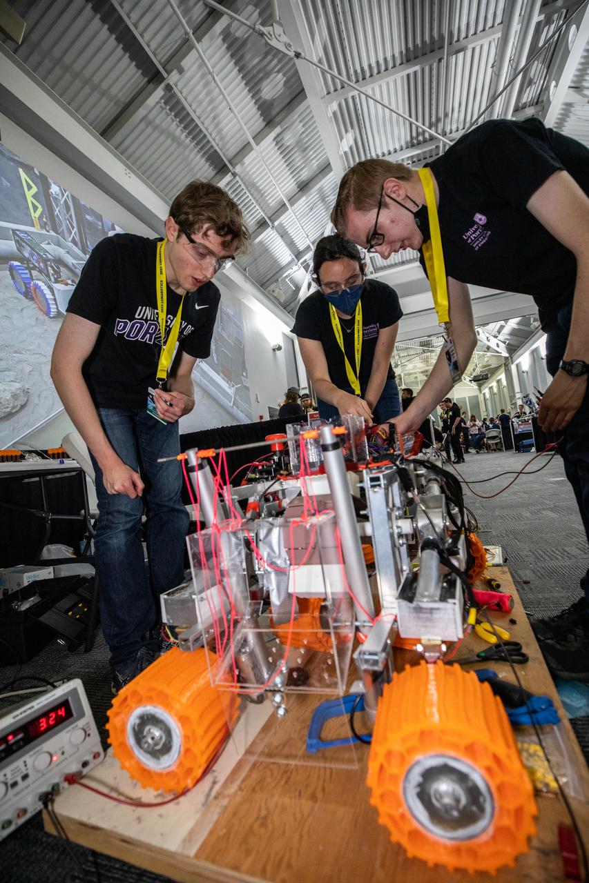 Students from the University of Portland in Oregon prepare their robot miner for its turn to dig in the mining arena during NASA’s LUNABOTICS competition on May 26, 2022, at the Center for Space Education near the Kennedy Space Center Visitor Complex in Florida. More than 35 teams from around the U.S. have designed and built remote-controlled robots for the mining competition. Teams use their semi-autonomous or remote-controlled robots to maneuver and dig in a supersized sandbox filled with rocks and simulated lunar soil, or regolith. The objective of the challenge is to see which team’s robot can collect and deposit the most rocky regolith within a specified amount of time. 