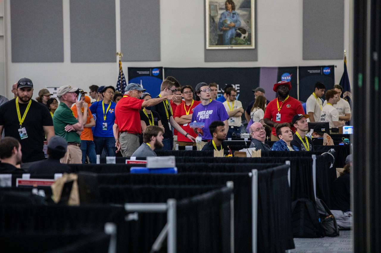 Team members from various colleges and universities watch a jumbo screen as robotic miners dig in the mining arena during NASA’s LUNABOTICS competition on May 26, 2022, at the Center for Space Education near the Kennedy Space Center Visitor Complex in Florida. More than 35 teams from around the U.S. have designed and built remote-controlled robots for the mining competition. Teams use their semi-autonomous or remote-controlled robots to maneuver and dig in a supersized sandbox filled with rocks and simulated lunar soil, or regolith. The objective of the challenge is to see which team’s robot can collect and deposit the most rocky regolith within a specified amount of time.