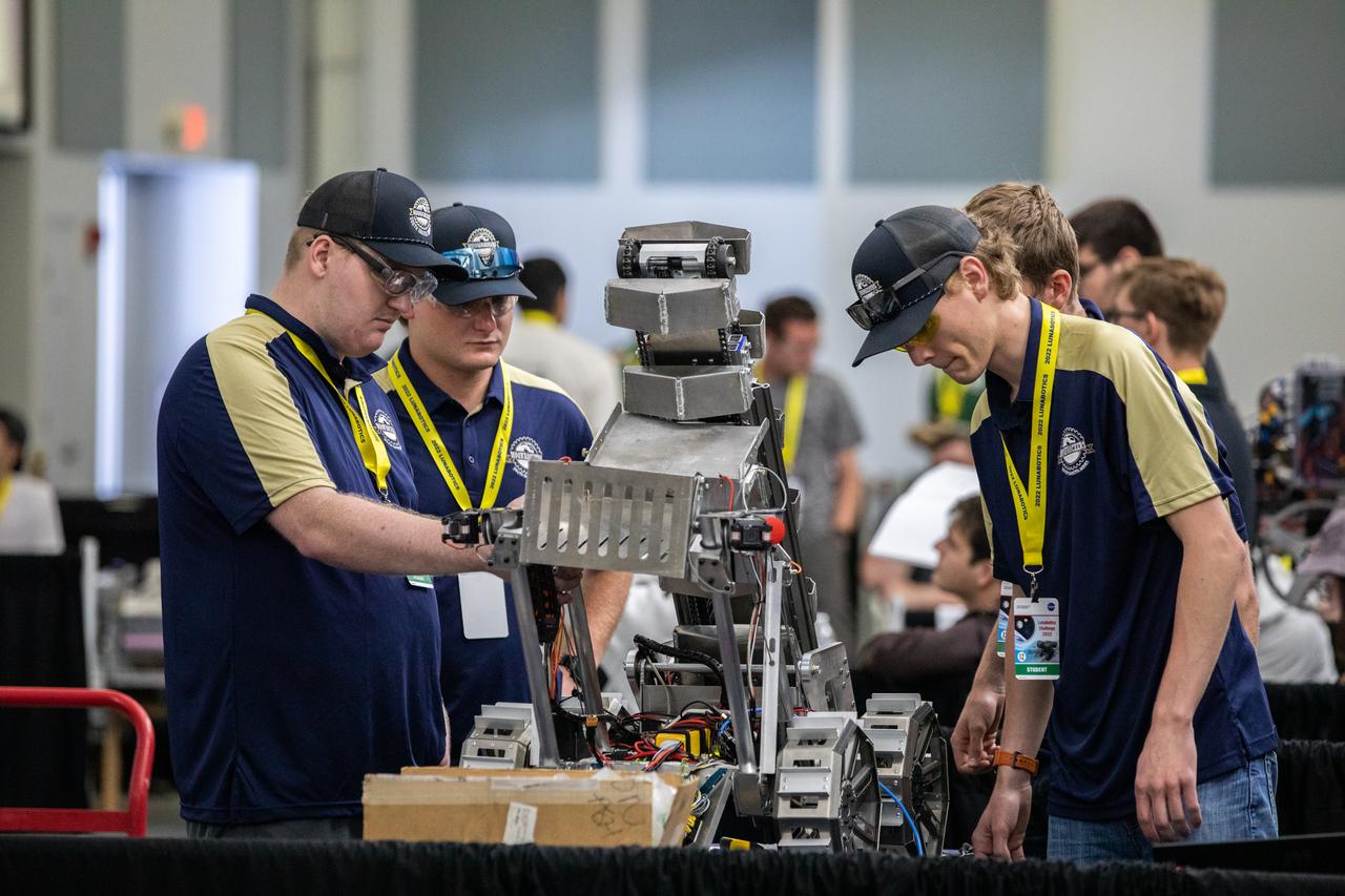 Team members from the South Dakota School of Mines and Technology prepare their robotic miner for its turn to dig in the mining arena during NASA’s LUNABOTICS competition on May 26, 2022, at the Center for Space Education near the Kennedy Space Center Visitor Complex in Florida. More than 35 teams from around the U.S. have designed and built remote-controlled robots for the mining competition. Teams use their semi-autonomous or remote-controlled robots to maneuver and dig in a supersized sandbox filled with rocks and simulated lunar soil, or regolith. The objective of the challenge is to see which team’s robot can collect and deposit the most rocky regolith within a specified amount of time. 