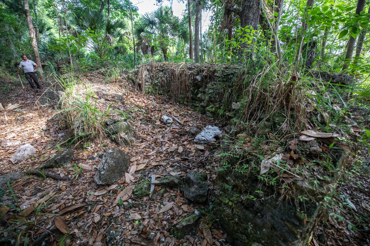Michael Legare, of the U.S. Fish and Wildlife Service, stands near the archeological ruins of the Elliot Plantation sugar mill at NASA’s Kennedy Space Center in Florida on May 26, 2022. The plantation’s enslaved community built the sugar mill structure, or sugar train, where sugar cane juice would be boiled during processing in graduated copper kettles until the liquid reduced into a thick syrup. The ruins of Elliot Plantation date from the 1760s and represent the largest, earliest, and southernmost British period sugar plantation in the U.S., as well as one of the most intact and best examples of a completely preserved enslaved landscape. The archeological site is managed through interagency cooperation between the National Park Service, the U.S. Fish and Wildlife Service, and NASA.
