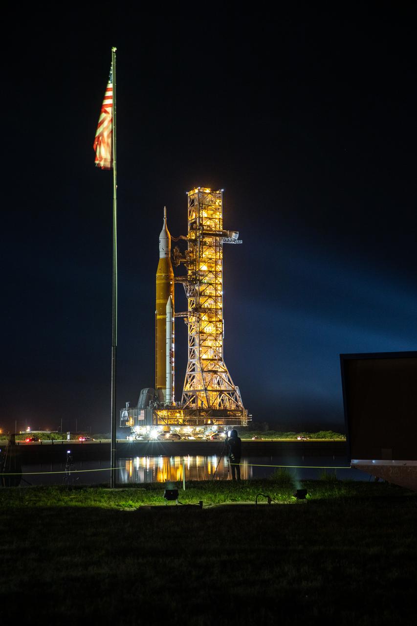 NASA’s Artemis I Moon rocket – carried atop the crawler-transporter 2 – prepares to roll past the iconic countdown clock at the NASA News Center on its way to Launch Complex 39B on June 6, 2022, at the agency’s Kennedy Space Center in Florida. The rocket is traveling to the launch pad for NASA’s next wet dress rehearsal attempt ahead of the Artemis I launch. The first in an increasingly complex series of missions, Artemis I will test the Space Launch System rocket and Orion spacecraft as an integrated system prior to crewed flights to the Moon. Through Artemis, NASA will land the first woman and first person of color on the lunar surface, paving the way for a long-term lunar presence and using the Moon as a steppingstone before venturing to Mars.