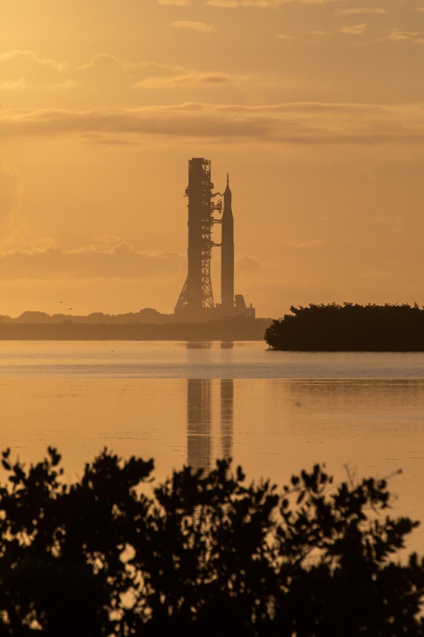 A sunrise at NASA’s Kennedy Space Center in Florida casts an orange glow around the agency’s Artemis I Moon rocket as it travels to Launch Complex 39B on June 6, 2022. The rocket rolled out of the Vehicle Assembly Building in the early morning hours to travel the 4.2 miles to the launch pad for NASA’s next wet dress rehearsal attempt ahead of the Artemis I launch. The first in an increasingly complex series of missions, Artemis I will test the Space Launch System rocket and Orion spacecraft as an integrated system prior to crewed flights to the Moon. Through Artemis, NASA will land the first woman and first person of color on the lunar surface, paving the way for a long-term lunar presence and using the Moon as a steppingstone before venturing to Mars.