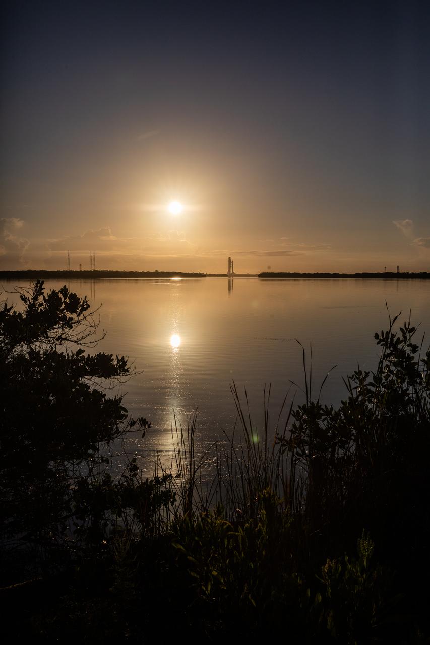 As the Sun rises bright in the sky, NASA’s Artemis I Moon rocket – carried atop the crawler-transporter 2 – can be seen from afar as it approaches Launch Complex 39B at NASA’s Kennedy Space Center in Florida on June 6, 2022. The rocket rolled out of the Vehicle Assembly Building in the early morning hours to travel the 4.2 miles to the launch pad for NASA’s next wet dress rehearsal attempt ahead of the Artemis I launch. The first in an increasingly complex series of missions, Artemis I will test the Space Launch System rocket and Orion spacecraft as an integrated system prior to crewed flights to the Moon. Through Artemis, NASA will land the first woman and first person of color on the lunar surface, paving the way for a long-term lunar presence and using the Moon as a steppingstone before venturing to Mars.