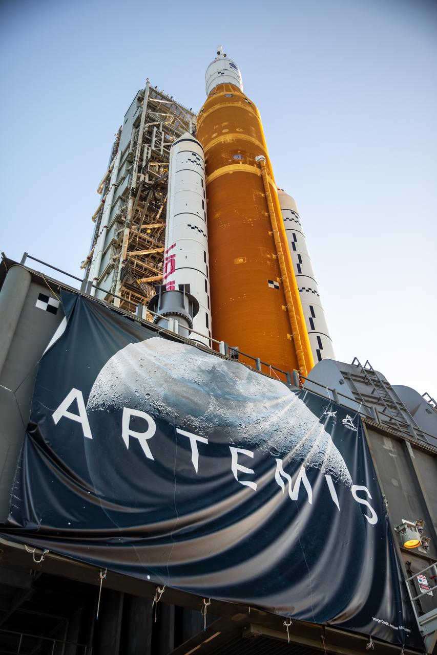 In this view looking up, NASA’s crawler-transporter 2 – adorned with an Artemis banner – can be seen bearing the weight of the agency’s Artemis I Moon rocket and mobile launcher as it carries the duo to Kennedy Space Center’s Launch Complex 39B in Florida on June 6, 2022. The rocket rolled out of the Vehicle Assembly Building in the early morning hours to travel the 4.2 miles to the launch pad for NASA’s next wet dress rehearsal attempt ahead of the Artemis I launch. The first in an increasingly complex series of missions, Artemis I will test the Space Launch System rocket and Orion spacecraft as an integrated system prior to crewed flights to the Moon. Through Artemis, NASA will land the first woman and first person of color on the lunar surface, paving the way for a long-term lunar presence and using the Moon as a steppingstone before venturing to Mars.