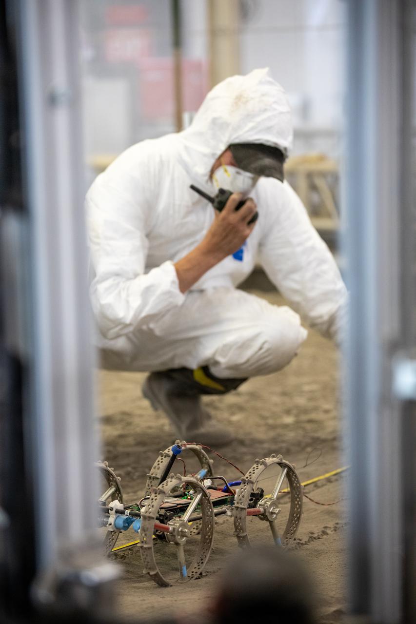 Senior Software Engineer Taylor Whitaker reports the results of a drawbar pull run to Astrobotic staff outside of the Granular Mechanics and Regolith Operations (GMRO) Laboratory’s regolith pit at NASA Kennedy Space Center’s Swamp Works facility on June 30, 2022. Astrobotic – a Pittsburgh-based space robotics company – is using the GMRO lab’s regolith bin, which holds approximately 120 tons of lunar regolith simulant, to depict how the company’s CubeRover would perform on the Moon. NASA’s Small Business Innovation Research program provided the funding for initial development, and a $2 million Tipping Point award from the agency has provided additional funding for continued development into a more mature rover.