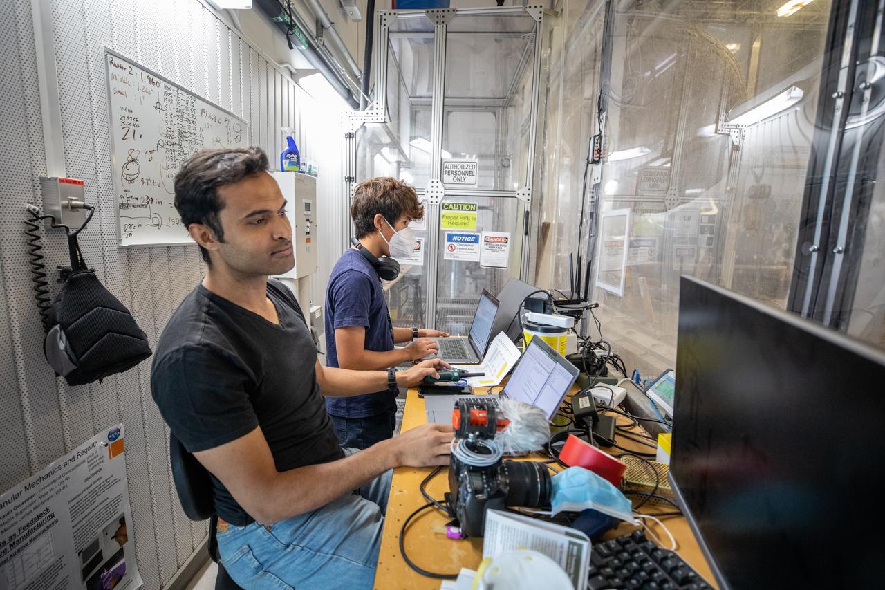 Senior Embedded Software Engineer Aamer Almujahed (left) and Software Engineering intern Ashten Akemoto run the ground software for Astrobotic’s CubeRover drawbar pull test inside the Granular Mechanics and Regolith Operations (GMRO) Laboratory’s regolith pit at NASA Kennedy Space Center’s Swamp Works facility on June 30, 2022. Astrobotic – a Pittsburgh-based space robotics company – is using the GMRO lab’s regolith bin, which holds approximately 120 tons of lunar regolith simulant, to depict how the company’s CubeRover would perform on the Moon. NASA’s Small Business Innovation Research program provided the funding for initial development, and a $2 million Tipping Point award from the agency has provided additional funding for continued development into a more mature rover.