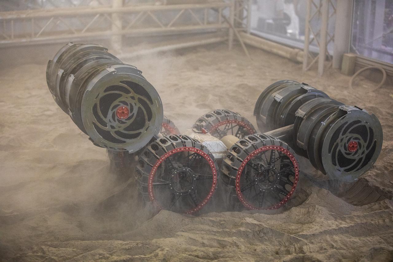 The ISRU Pilot Excavator digs in the regolith bin during testing inside Swamp Works at NASA’s Kennedy Space Center in Florida on July 28, 2022. Tests use a gravity assist offload system to simulate reduced gravity conditions found on the Moon. On the surface of the Moon, mining robots like the Pilot Excavator will excavate the regolith and take the material to a processing plant where usable elements such as hydrogen, oxygen and water can be extracted for life support systems. The Pilot Excavator can scoop up icy regolith which can be used to make operations on the Moon sustainable.