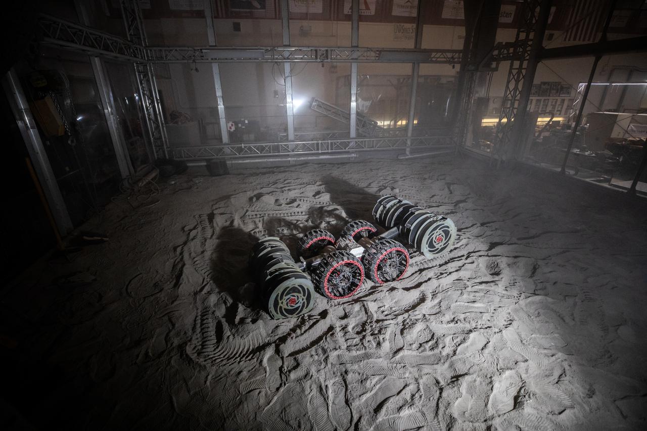 With the lights out, the ISRU Pilot Excavator digs in regolith bin during testing inside Swamp Works at NASA’s Kennedy Space Center in Florida on July 28, 2022. Tests use a gravity assist offload system to simulate reduced gravity conditions found on the Moon. On the surface of the Moon, mining robots like the Pilot Excavator will excavate the regolith and take the material to a processing plant where usable elements such as hydrogen, oxygen and water can be extracted for life support systems. The Pilot Excavator can scoop up icy regolith which can be used to make operations on the Moon sustainable.