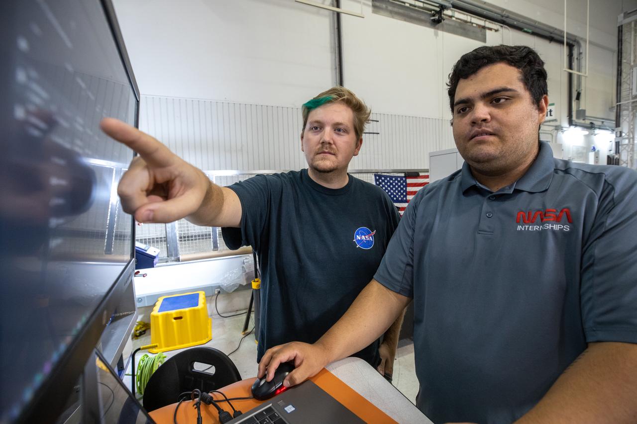 NASA engineer Evan Bell, left, and NASA Internships, Fellowships, and Scholarships (NIFS) intern Leonel Herrera test a 3D printer on July 28, 2022, at Swamp Works at NASA’s Kennedy Space Center in Florida, as part of the Relevant Environment Additive Construction Technology (REACT) project. Among the key objectives of the project is developing an architectural and structural design for a shelter that provides protection to habitable assets on the lunar surface. Testing REACT derives from NASA’s 2020 Announcement of Collaboration Opportunity with AI SpaceFactory – an architectural and construction technology company and winner of NASA’s 3D Printed Habitat Challenge.