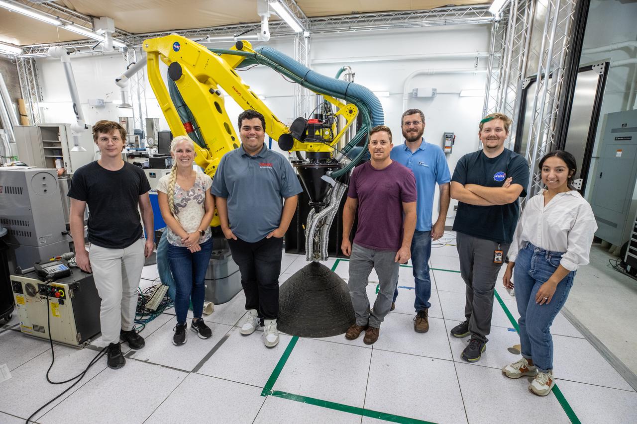A team at NASA’s Kennedy Space Center in Florida poses with a Zero Launch Mass 3D printer on July 28, 2022, at the Florida spaceport’s Swamp Works, as part of the Relevant Environment Additive Construction Technology (REACT) project. Shown from left to right are: Tommy Lipscomb, materials engineer; Tesia Irwin, chemist; Leonel Herrera, NASA Internships, Fellowships, and Scholarships (NIFS) intern; Nathan Gelino, principal investigator; Matt Nugent, robotics engineer; Evan Bell, robotics engineer; and Nilab Azim, chemist. Among the key objectives of the project is developing an architectural and structural design for a shelter that provides protection to habitable assets on the lunar surface. Testing REACT derives from NASA’s 2020 Announcement of Collaboration Opportunity with AI SpaceFactory – an architectural and construction technology company and winner of NASA’s 3D Printed Habitat Challenge.