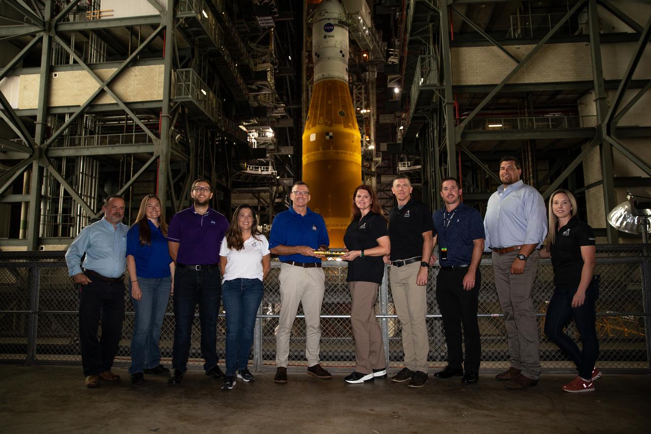 Cliff Lanham, fifth from the left, ground operations manager with NASA’s Exploration Ground Systems (EGS), hands off the baton to Charlie Blackwell-Thompson, Artemis I launch director, inside the Vehicle Assembly building at NASA’s Kennedy Space Center in Florida on Aug. 15, 2022. Also pictured are members of Kennedy’s EGS and Artemis launch teams. NASA’s Space Launch System (SLS) rocket, with the agency’s Orion spacecraft atop, is targeted to start its rollout to Launch Pad 39B on Aug. 16 at approximately 9 p.m., in preparation for the Artemis I launch – set for no earlier than Aug. 29. Artemis I will be the first integrated test of the SLS and Orion. In later missions, NASA will land the first woman and the first person of color on the Moon, paving the way for a long-term lunar presence and serving as a steppingstone on the way to Mars.