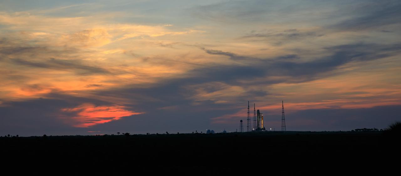 A sunrise view of NASA’s Space Launch System and Orion spacecraft for Artemis I on the pad at Launch Complex 39B at NASA’s Kennedy Space Center in Florida on Aug. 18, 2022. Launch of Artemis I is scheduled for no earlier than Aug. 29, 2022, at 8:34 a.m. EDT. The first in a series of increasingly complex missions, Artemis I will provide a foundation for human deep space exploration and demonstrate our commitment and capability to extend human presence to the Moon and beyond. The primary goal of Artemis I is to thoroughly test the integrated systems before crewed missions by operating the spacecraft in a deep space environment, testing Orion’s heat shield, and recovering the crew module after reentry, descent, and splashdown. 