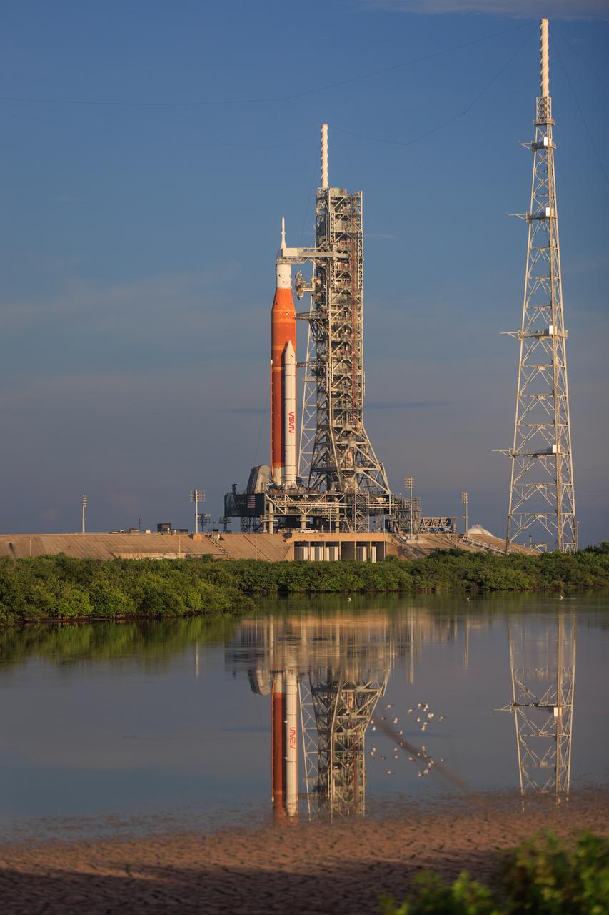 NASA’s Artemis I Space Launch System and Orion spacecraft atop the mobile launcher on the pad at Launch Complex 39B at the agency’s Kennedy Space Center in Florida are reflected in the nearby waterway on Aug. 19, 2022. Launch of Artemis I is scheduled for no earlier than Aug. 29, 2022, at 8:33 a.m. EDT. The first in a series of increasingly complex missions, Artemis I will provide a foundation for human deep space exploration and demonstrate our commitment and capability to extend human presence to the Moon and beyond. The primary goal of Artemis I is to thoroughly test the integrated systems before crewed missions by operating the spacecraft in a deep space environment, testing Orion’s heat shield, and recovering the crew module after reentry, descent, and splashdown. 