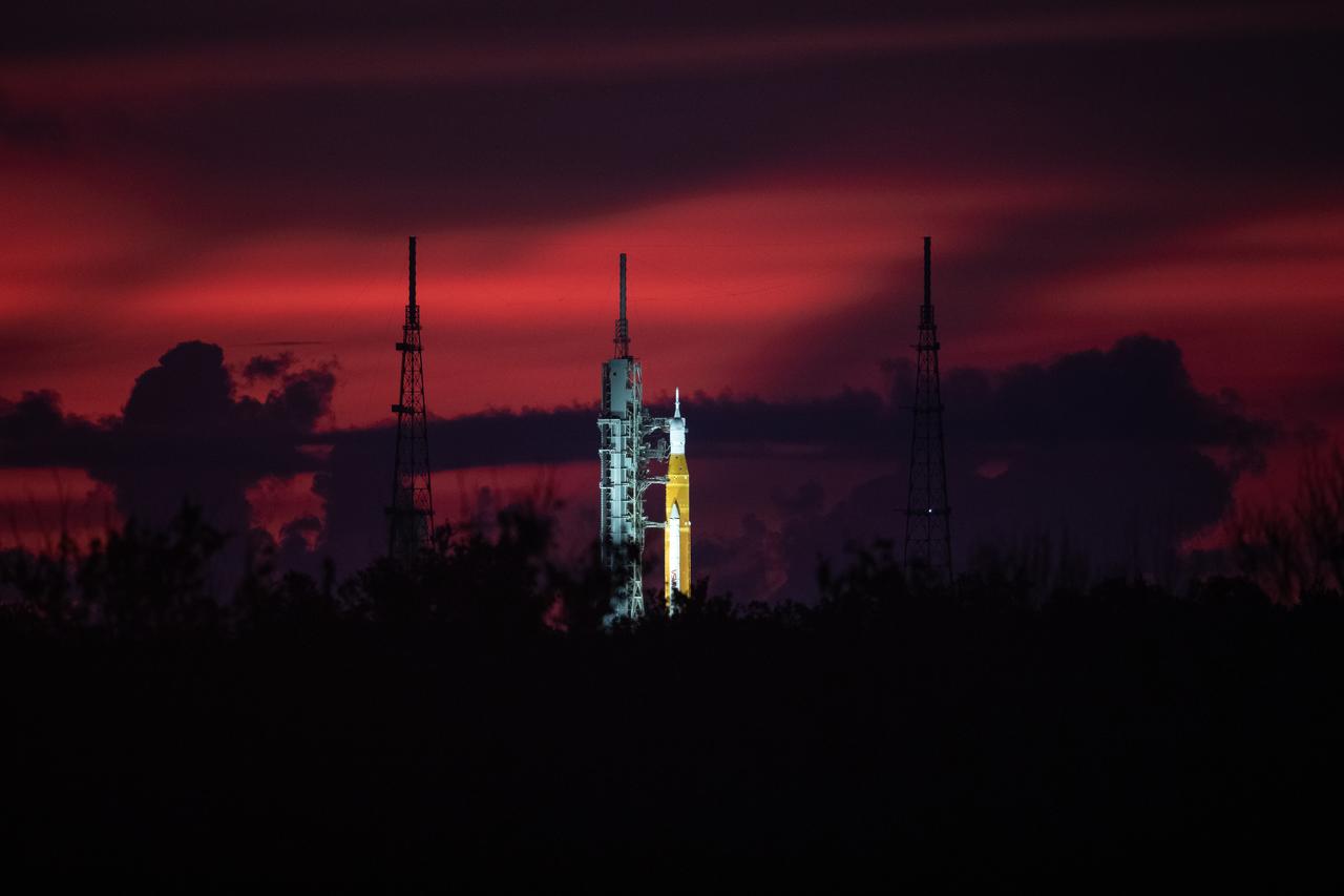 A sunrise view of NASA’s Space Launch System and Orion spacecraft for Artemis I on the pad at Launch Complex 39B at NASA’s Kennedy Space Center in Florida on Aug. 22, 2022. Launch of Artemis I is scheduled for no earlier than Aug. 29, 2022, at 8:33 a.m. EDT. The first in a series of increasingly complex missions, Artemis I will provide a foundation for human deep space exploration and demonstrate our commitment and capability to extend human presence to the Moon and beyond. The primary goal of Artemis I is to thoroughly test the integrated systems before crewed missions by operating the spacecraft in a deep space environment, testing Orion’s heat shield, and recovering the crew module after reentry, descent, and splashdown. 