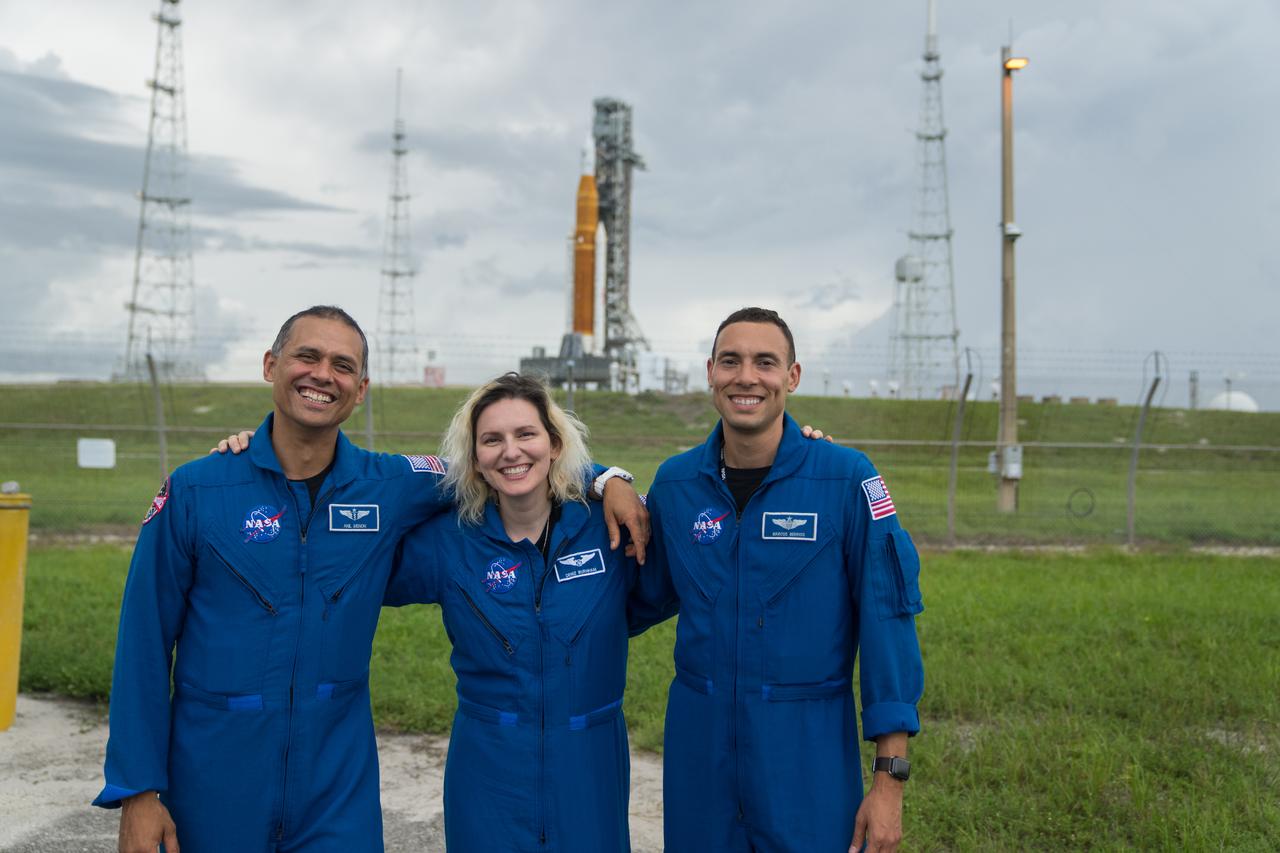 From left to right, NASA astronaut candidates Anil Menon, Deniz Burnham, and Marcos Berrios pose for a photograph in front of NASA’s Artemis I Space Launch System and Orion spacecraft atop the mobile launcher on the pad at Launch Complex 39B at the agency’s Kennedy Space Center in Florida on Sept. 2, 2022. The first in a series of increasingly complex missions, Artemis I will provide a foundation for human deep space exploration and demonstrate our commitment and capability to extend human presence to the Moon and beyond. The primary goal of Artemis I is to thoroughly test the integrated systems before crewed missions by operating the spacecraft in a deep space environment, testing Orion’s heat shield, and recovering the crew module after reentry, descent, and splashdown. In later missions, NASA will land the first woman and the first person of color on the surface of the Moon, paving the way for a long-term lunar presence and serving as a steppingstone on the way to Mars.