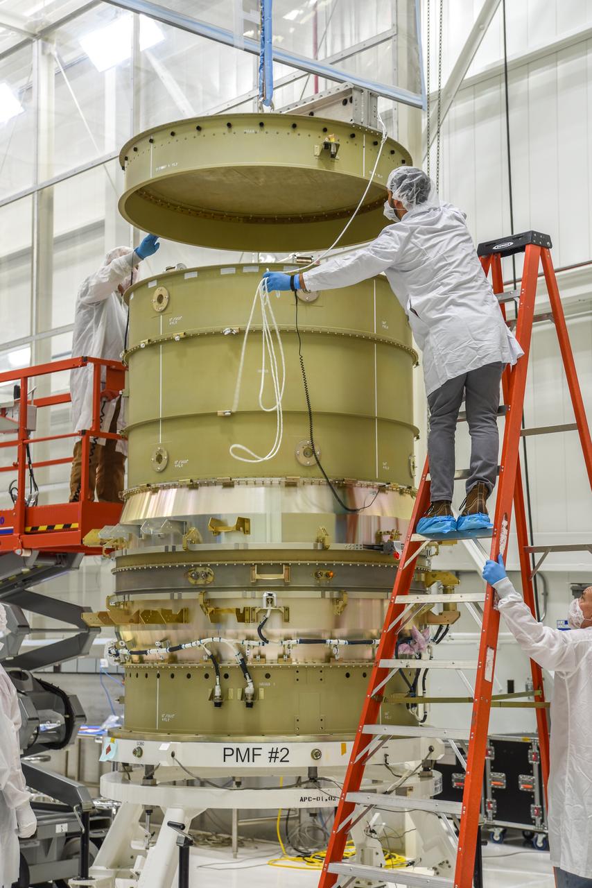 Technicians use a crane to attach the payload adapter separation systems canister to NASA’s Low-Earth Orbit Flight Test of an Inflatable Decelerator (LOFTID) payload stack as part of launch preparations occurring inside Building 836 at Vandenberg Space Force Base (VSFB) in California on Sept. 9, 2022. LOFTID is the secondary payload on the National Oceanic and Atmospheric Administration’s (NOAA) Joint Polar Satellite System-2 (JPSS-2) satellite mission. JPSS-2 is the third satellite in the Joint Polar Satellite System series. It is scheduled to lift off from VSFB on Nov. 1 from Space Launch Complex-3. JPSS-2, which will be renamed NOAA-21 after reaching orbit, will join a constellation of JPSS satellites that orbit from the North to the South pole, circling Earth 14 times a day and providing a full view of the entire globe twice daily. LOFTID will demonstrate inflatable heat shield technology that could enable a variety of proposed NASA missions to destinations such as Mars, Venus, and Titan, as well as returning heavier payloads from low-Earth orbit. 