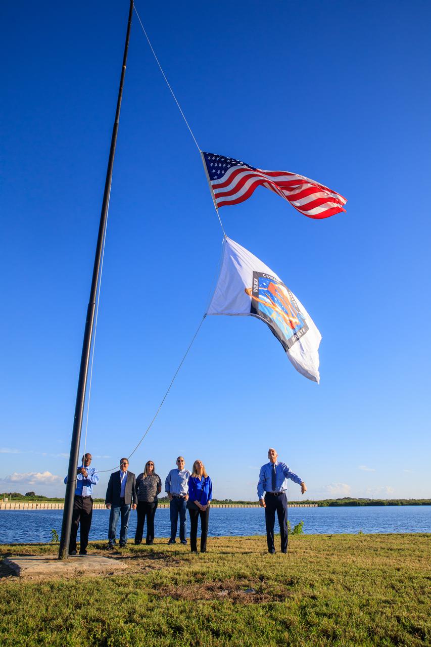 NASA Commercial Crew Program (CCP) employees Tyrell Hawkins (left) and Henry May (right) raise the Crew-5 flag near the countdown clock at the Press Site at NASA’s Kennedy Space Center in Florida on Oct. 3, 2022. In the center is CCP Manager Steve Stich. NASA’s SpaceX Crew-5 mission will carry NASA astronauts Josh Cassada and Nicole Aunapu Mann, Roscosmos cosmonaut Anna Kikina, and JAXA (Japan Aerospace Exploration Agency) to the International Space Station for a science expedition mission as part of the agency’s CCP. SpaceX’s Falcon 9 rocket and Crew Dragon Endurance spacecraft are scheduled to lift off from Kennedy’s Launch Complex 39A at noon EDT on Oct. 5, 2022.