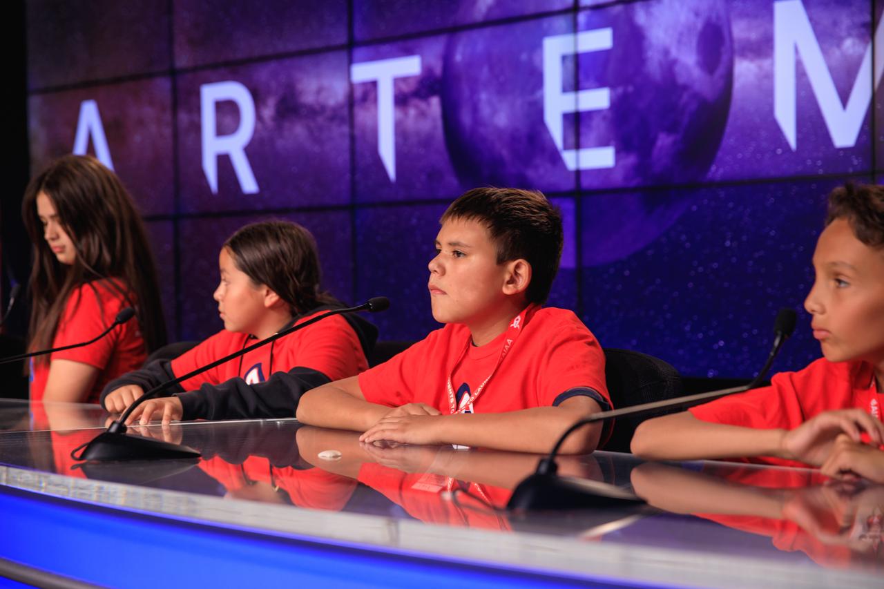 A group of students and their chaperones gather in the John Holliman Auditorium of the News Center to simulate a news conference during a tour of NASA’s Kennedy Space Center in Florida on Oct. 6, 2022. Some of them are seated at the dais at the front of the auditorium. The middle-school students, from the Boys and Girls Clubs of the Flathead Indian Reservation in Montana, are visiting the space center with the Students to Launch program. Students to Launch engages students in STEM (science, technology, engineering and mathematics) and creates awareness of careers in the space program. 