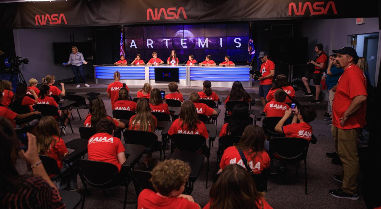 A group of students and their chaperones gather in the John Holliman Auditorium of the News Center to simulate a news conference during a tour of NASA’s Kennedy Space Center in Florida on Oct. 6, 2022. Some of them are seated at the dais at the front of the auditorium. At far left is Leah Martin, NASA Communications. The middle-school students, from the Boys and Girls Clubs of the Flathead Indian Reservation in Montana, are visiting the space center with the Students to Launch program. Students to Launch engages students in STEM (science, technology, engineering and mathematics) and creates awareness of careers in the space program. 