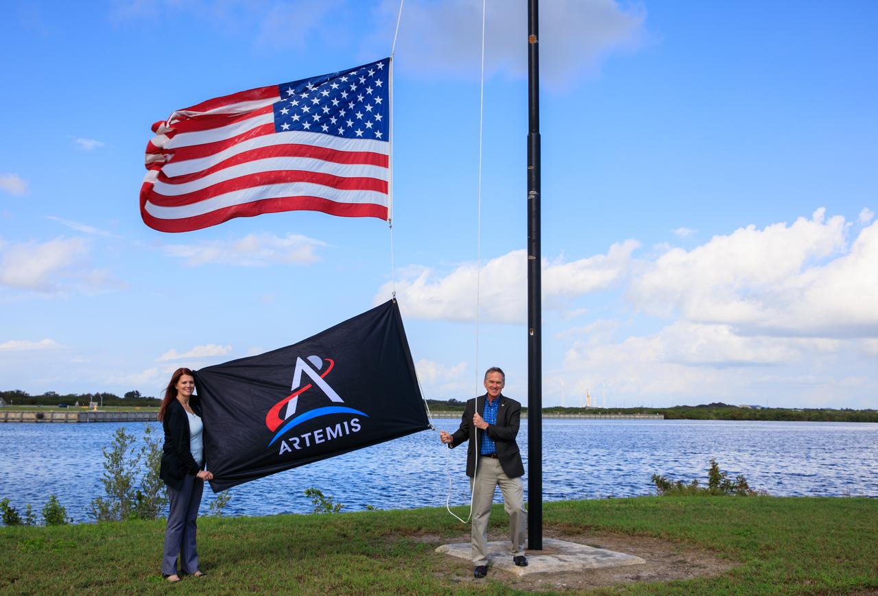 Artemis I Launch Director Charlie Blackwell-Thompson (left) and Exploration Ground Systems Manager Mike Bolger (right) raise the Artemis flag near the countdown clock at NASA’s Kennedy Space Center in Florida on Nov. 14, 2022. NASA’s Space Launch System (SLS) rocket and Orion spacecraft can be seen in the background at Kennedy’s Launch Pad 39B. The uncrewed Artemis I flight will be the first integrated test of the agency’s SLS rocket and Orion spacecraft and is scheduled to launch Wednesday, Nov. 16. The primary goal of Artemis I is to thoroughly test the integrated systems before crewed missions by launching Orion atop the SLS rocket, operating the spacecraft in a deep space environment, testing Orion’s heat shield, and recovering the crew module after reentry, descent, and splashdown. During the flight, Orion will launch atop the world’s most powerful rocket and fly farther than any human-rated spacecraft has ever flown, paving the way for human deep space exploration and demonstrating our commitment and capability to extend human presence to the Moon and beyond. 