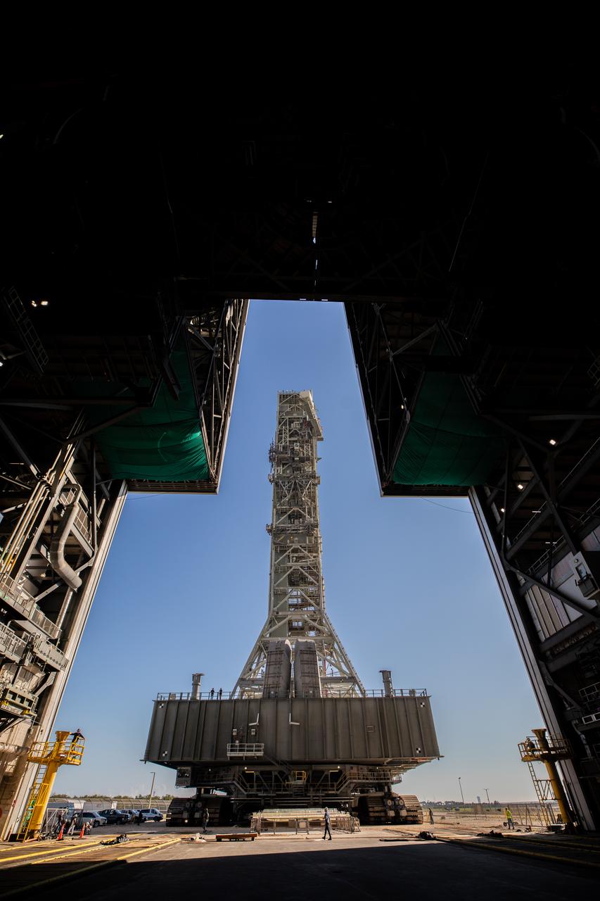 A view from inside the Vehicle Assembly Building (VAB) at NASA’s Kennedy Space Center in Florida on Dec. 9, 2022, as the mobile launcher, carried atop the crawler-transporter 2, arrives at the entrance to the transfer aisle, following the successful launch of the agency’s Space Launch System (SLS) rocket and Orion spacecraft on the Artemis I flight test on Nov. 16, 2022. The mobile launcher will stay inside the VAB and remain there for several weeks as teams get it ready for the Artemis II crewed mission. Following its stay in the VAB, it will go to the mobile launcher park site location at Kennedy where it will undergo emergency egress modifications and testing to support future Artemis missions. 