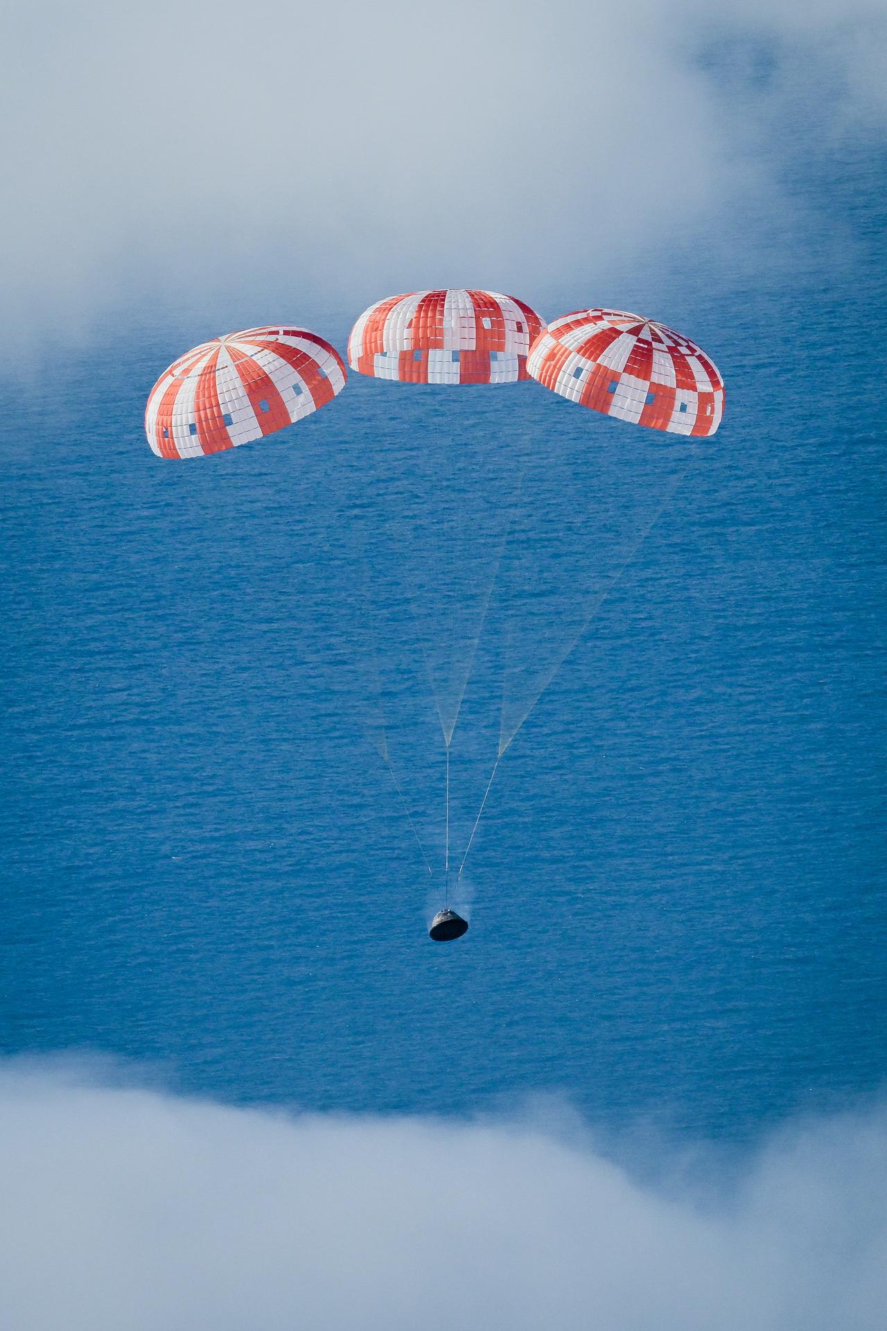 The Orion spacecraft drifts down toward the Pacific Ocean under its three main parachutes following its return to Earth at the conclusion of NASA's Artemis I mission.